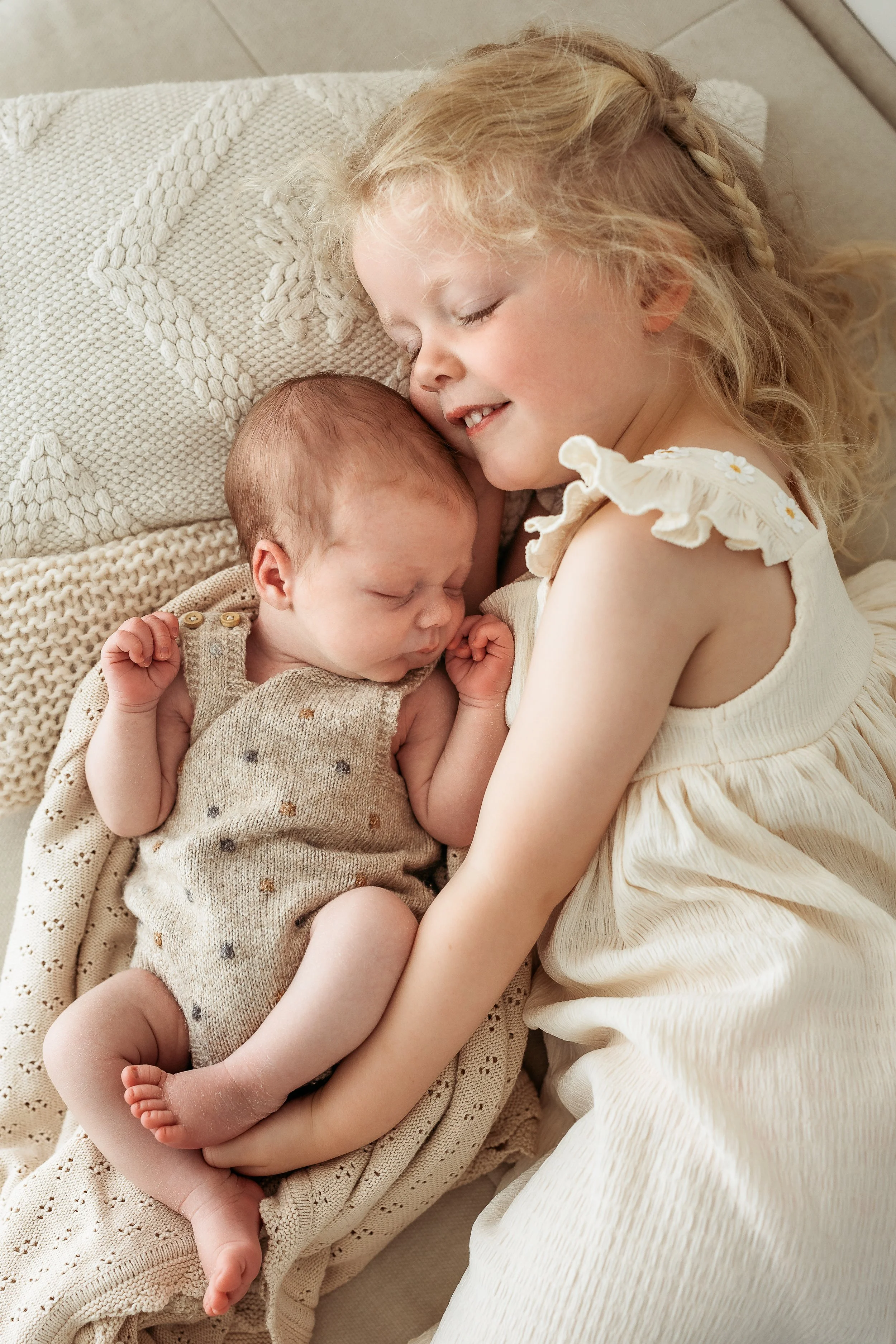 Older sibling cuddling their newborn baby during a relaxed family newborn photography session.