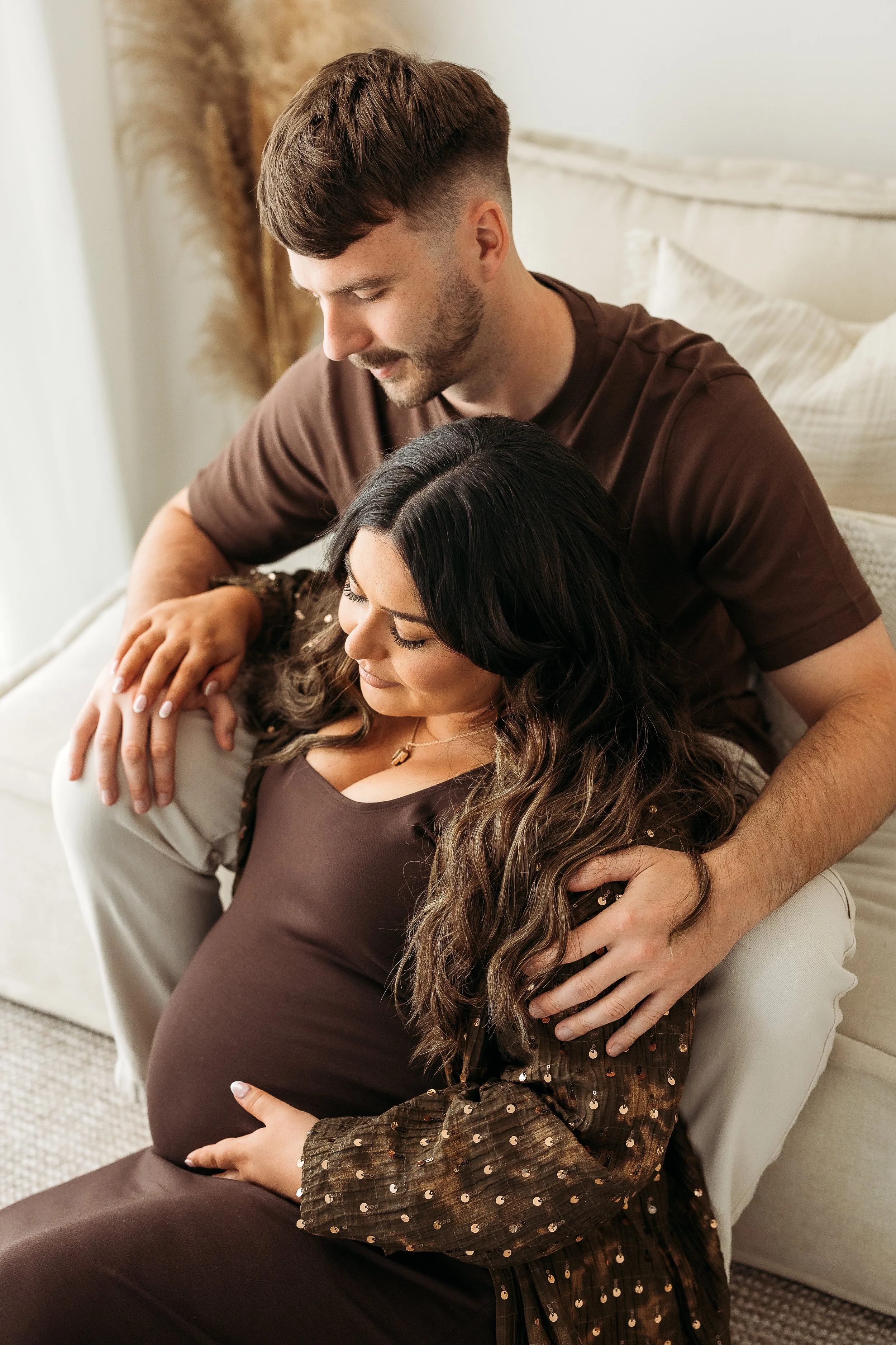 Expecting parents embracing and enjoying a quiet moment together during a natural maternity photography session.