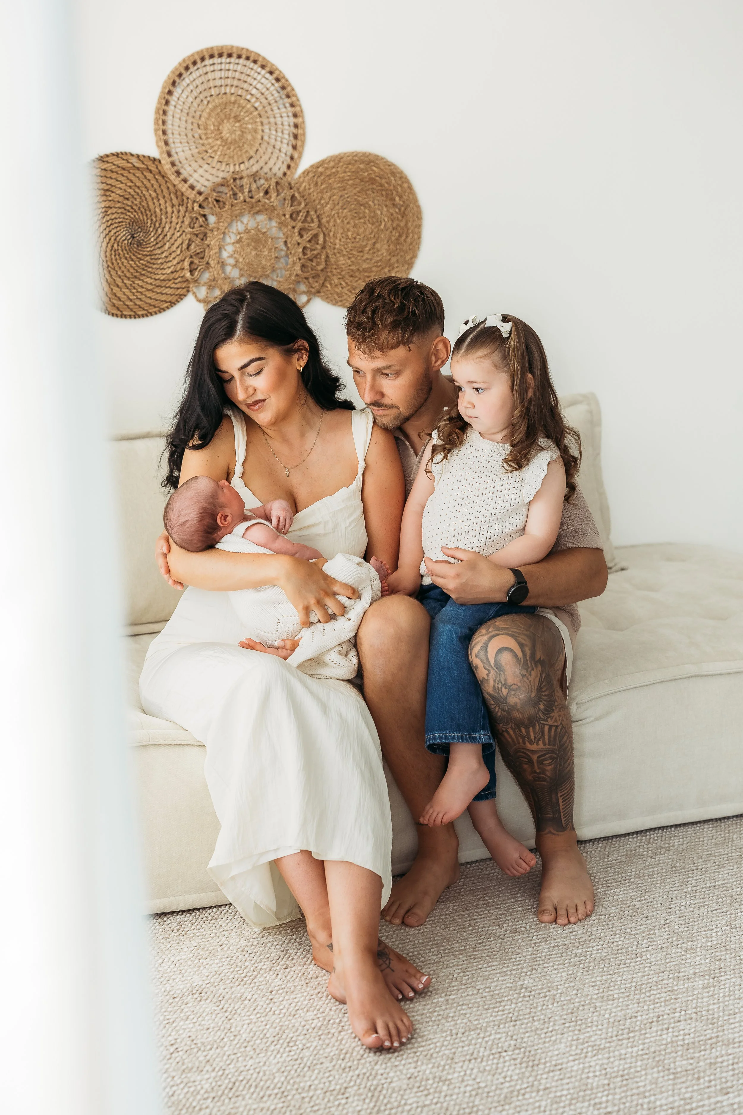 Parents and sibling cuddling their newborn baby during a natural newborn photography session.