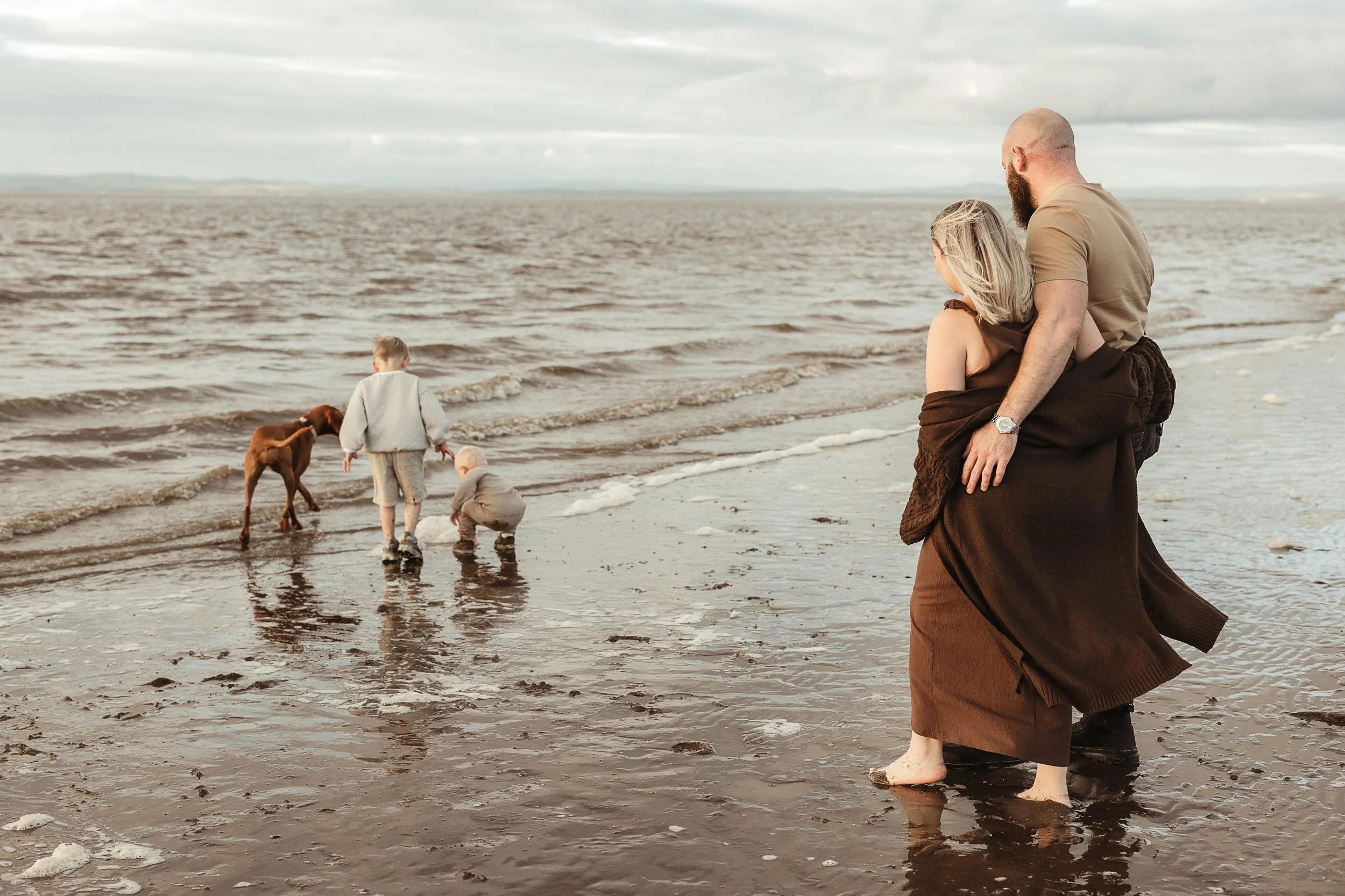 A family enjoying a relaxed beach adventure together with their children and dogs, capturing the connection, laughter and memories made outdoors.