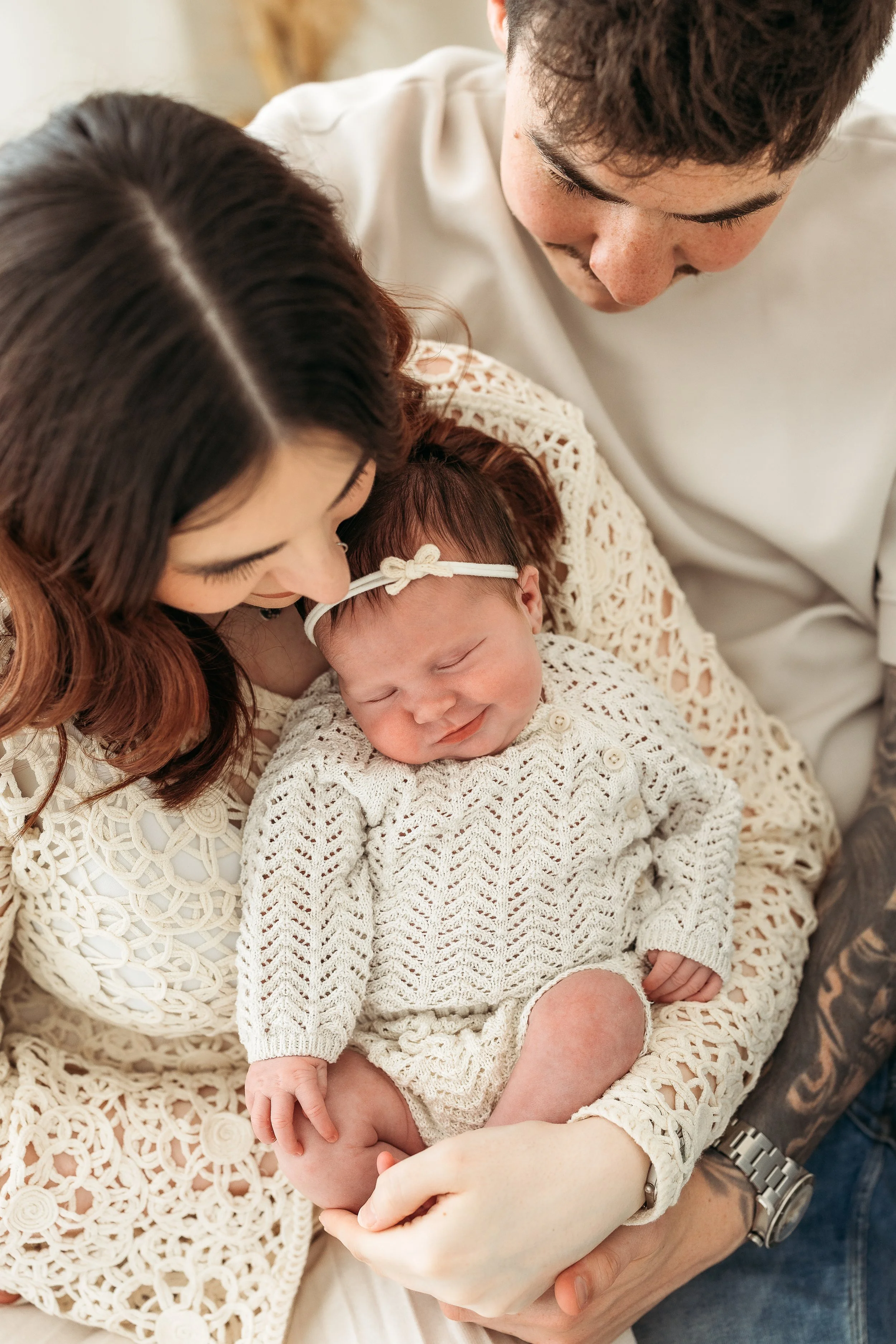 Parents cuddling their newborn baby girl during a relaxed newborn photography session.