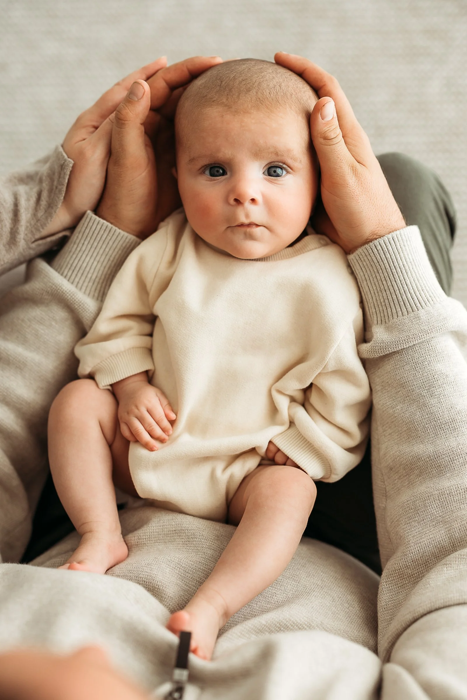 A young baby resting safely in loving hands, capturing the delicate details and connection of those early months.