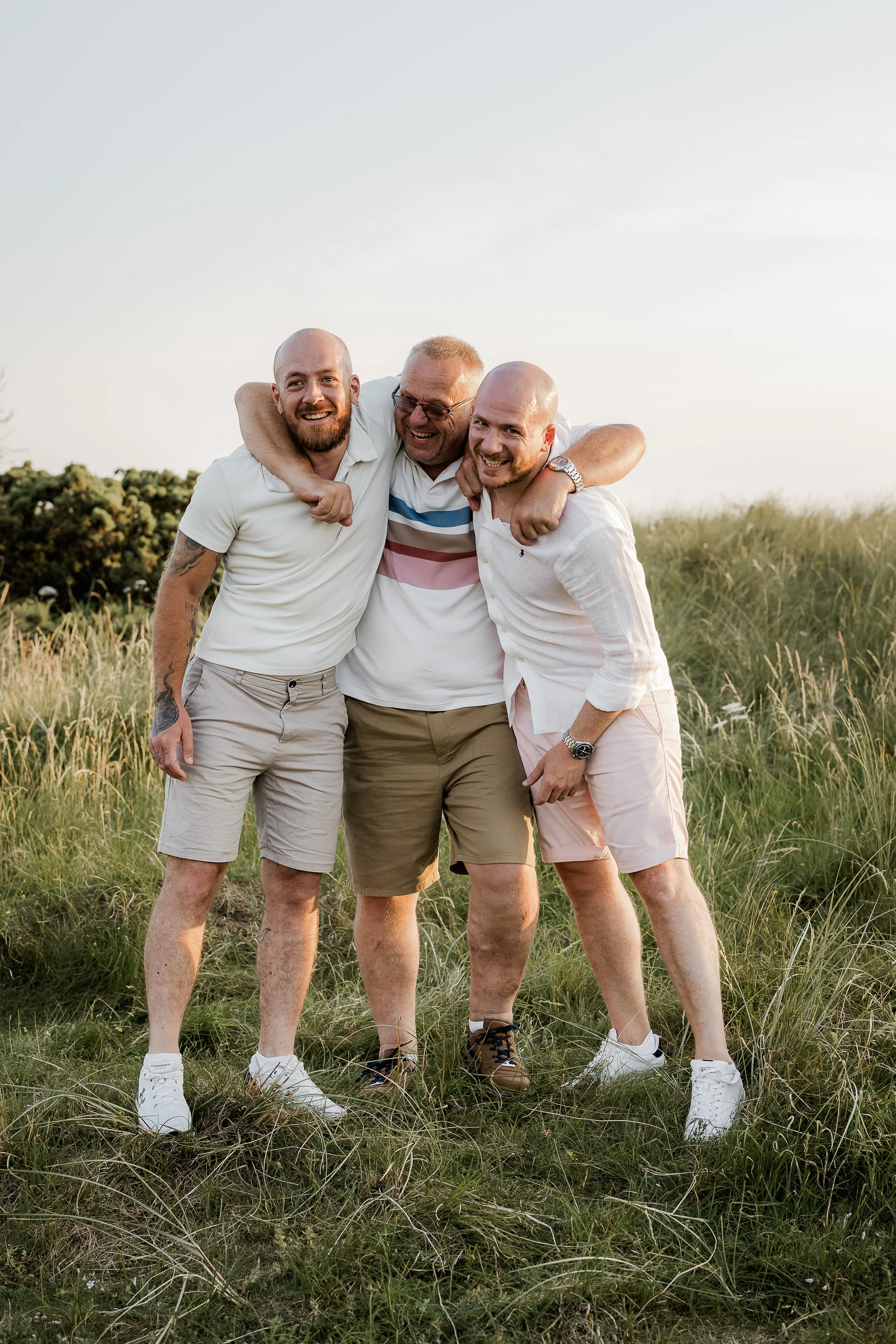A group of men sharing a joyful moment together outdoors, celebrating connection, laughter and the relationships that matter most during an extended family session.