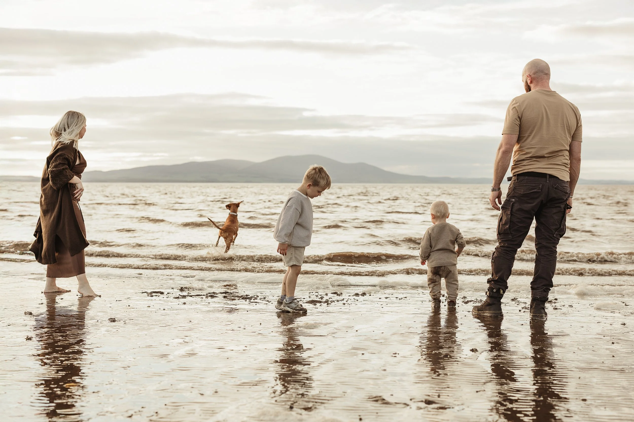 A family enjoying an outdoor adventure together with their dog, capturing connection, exploration and memories made by the sea.