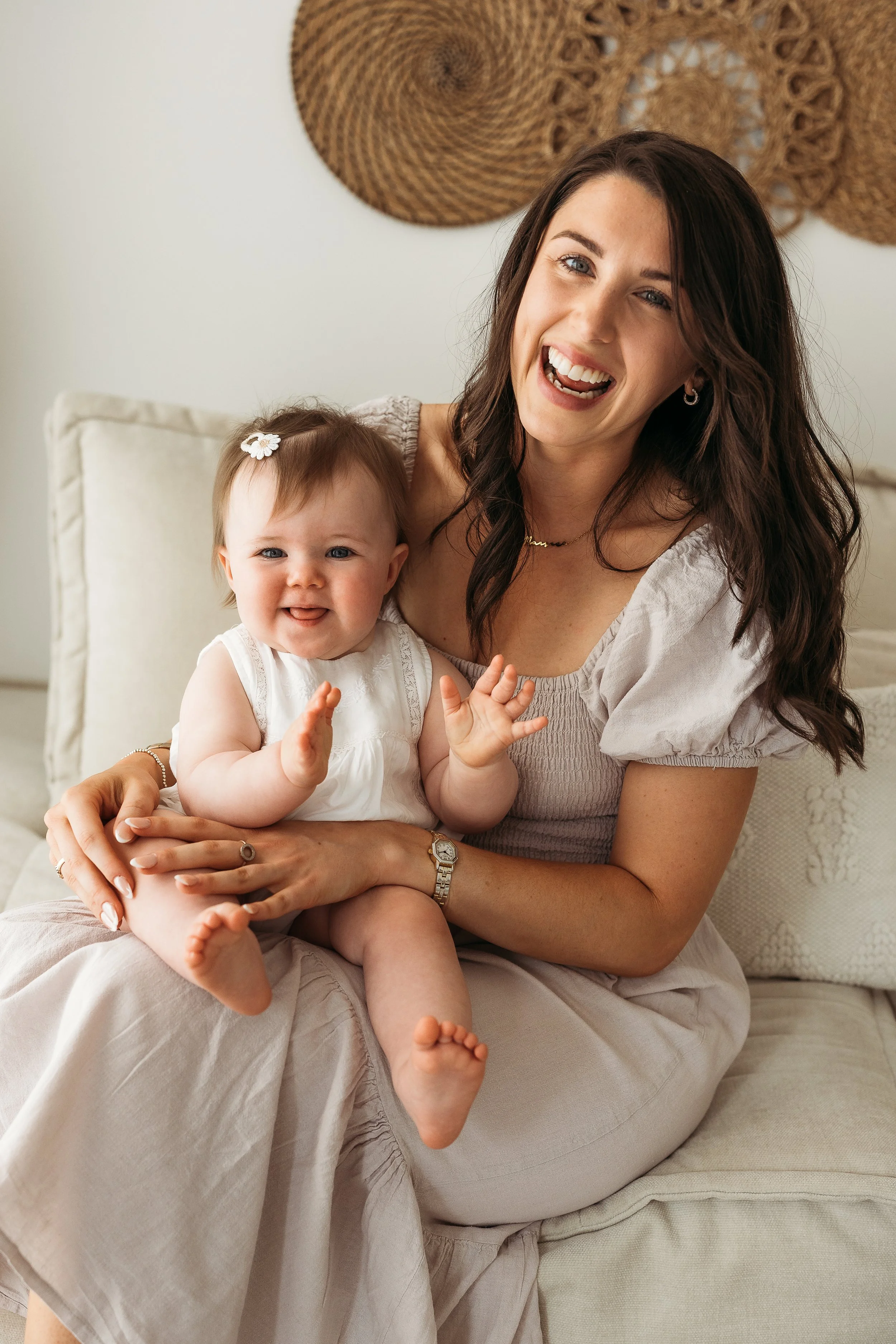 Mother cuddling her laughing baby during a relaxed first birthday photography session in a natural light studio