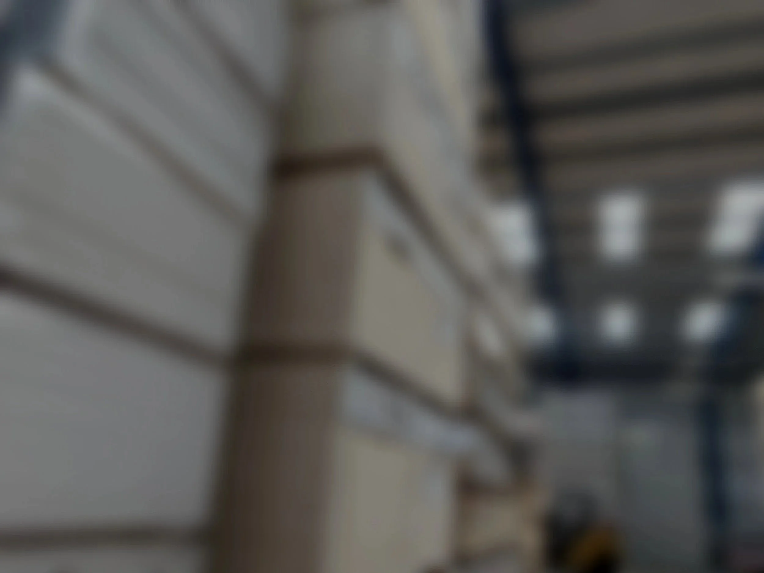Blurred stacks of panels stored vertically in a warehouse with a forklift in the background.