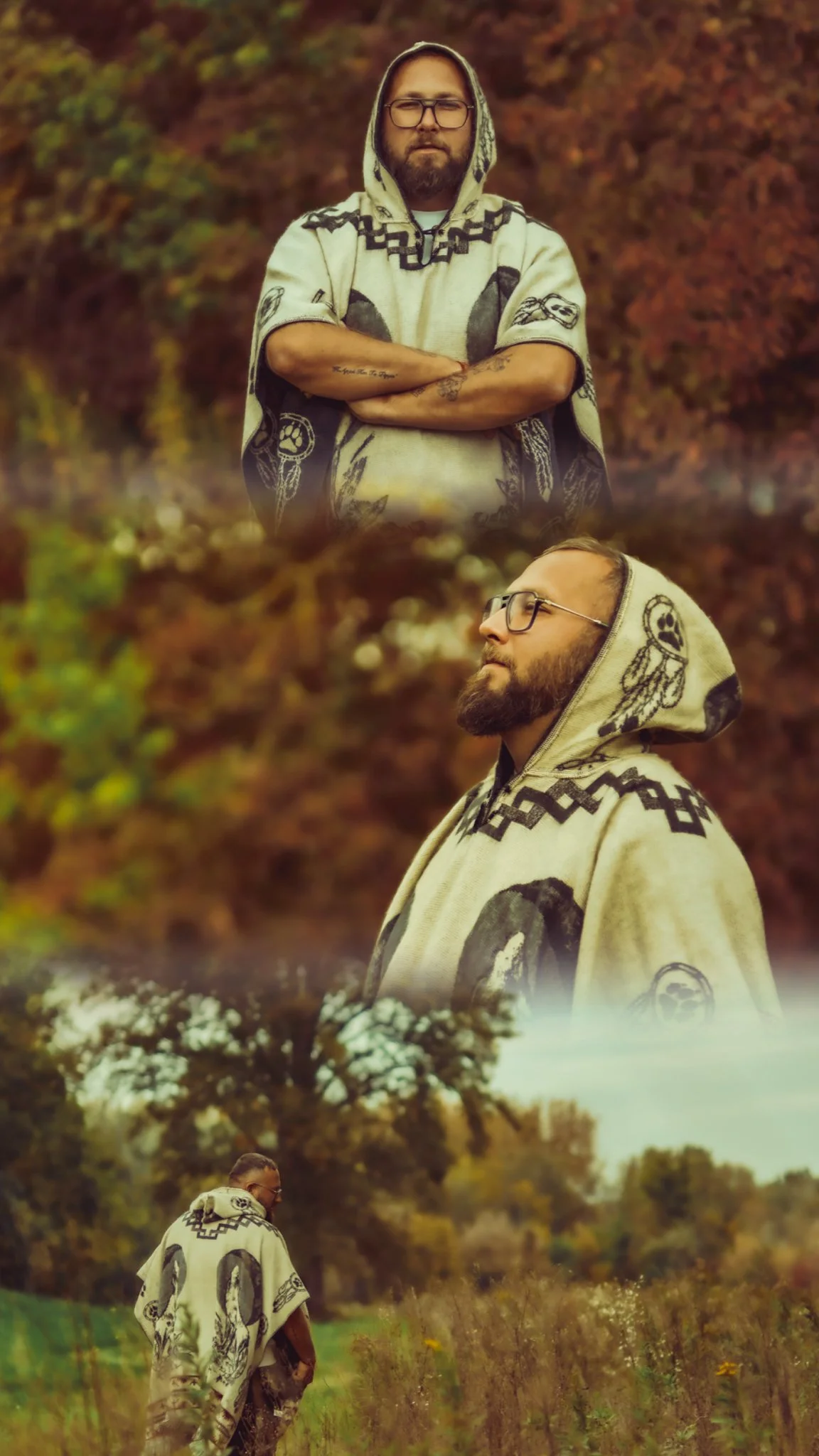 A man with glasses and a beard wearing a hoodie with black and white patterns, standing outdoors with arms crossed and looking directly at the camera, in front of colorful autumn trees.
