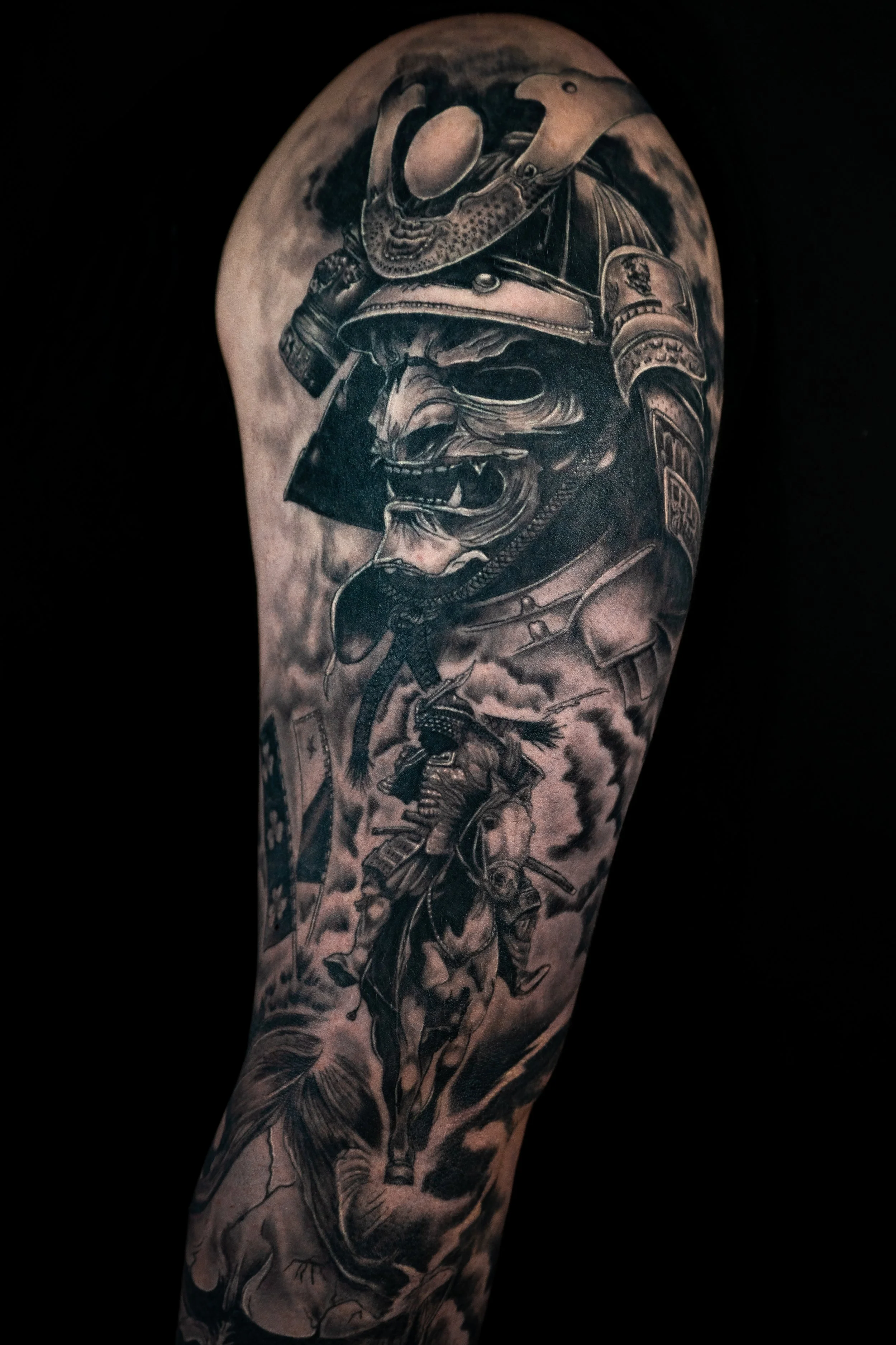 Tattoo of a fierce warrior wearing a helmet and armor, with an animalistic, snarling face and sharp teeth, on a person's arm.
