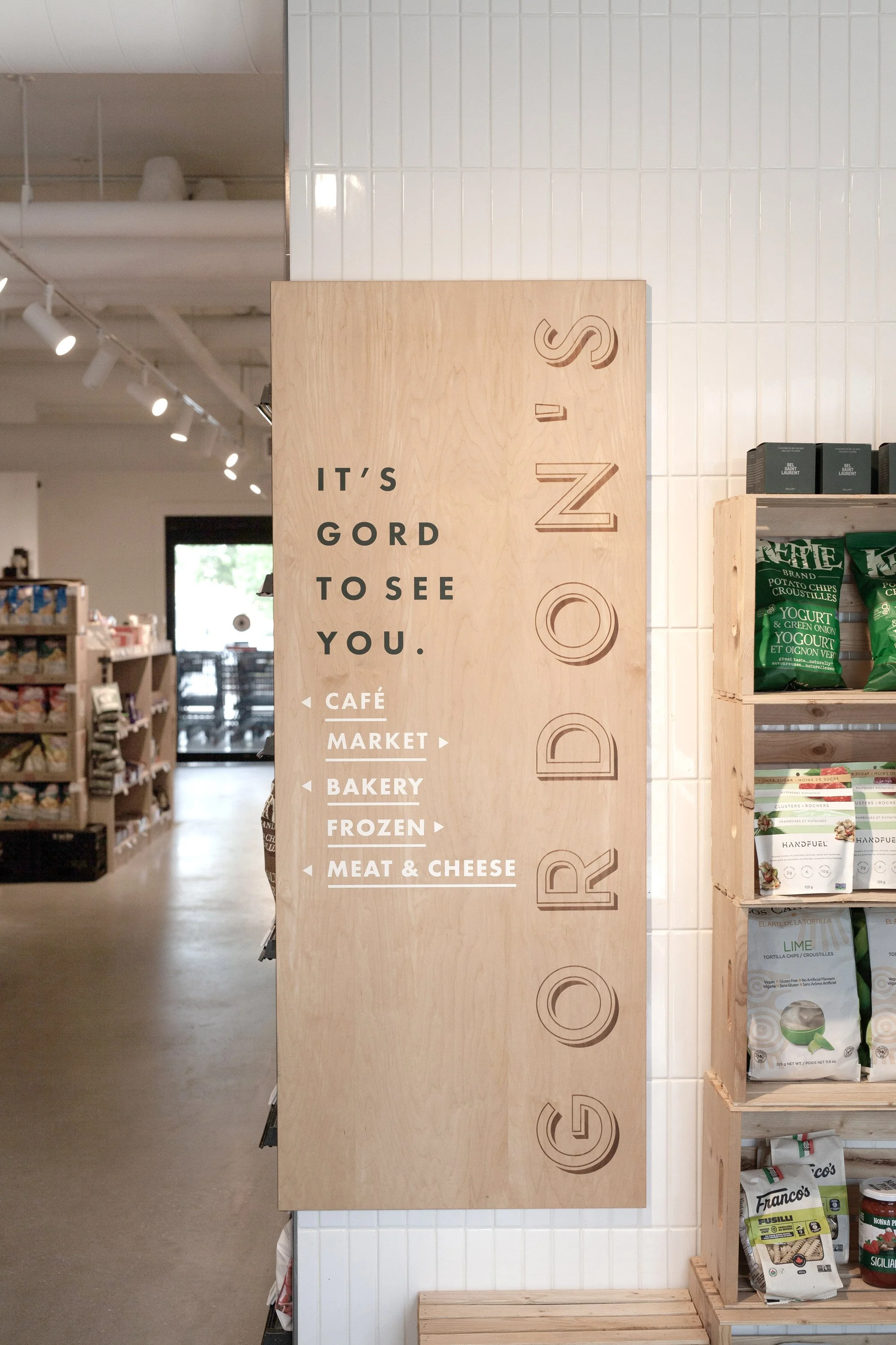 Store sign with the words 'It's gord to see you.' and a list of sections including Café, Market, Bakery, Frozen, Meat & Cheese.