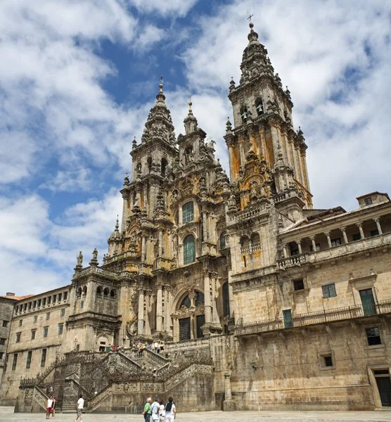 Historic cathedral with multiple towers, stone facade, and ornate architectural details under a partly cloudy sky.
