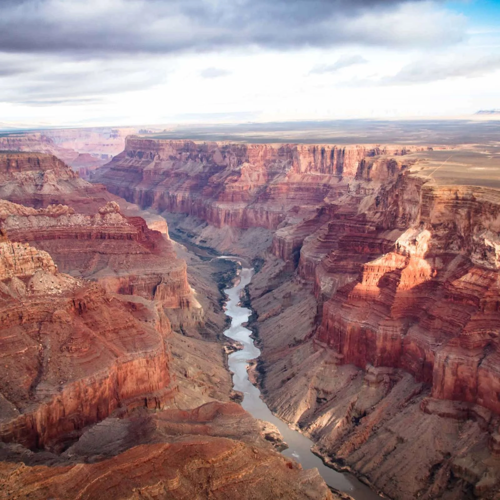 A view of the Grand Canyon showing layered red rock formations and the Colorado River flowing through the canyon.