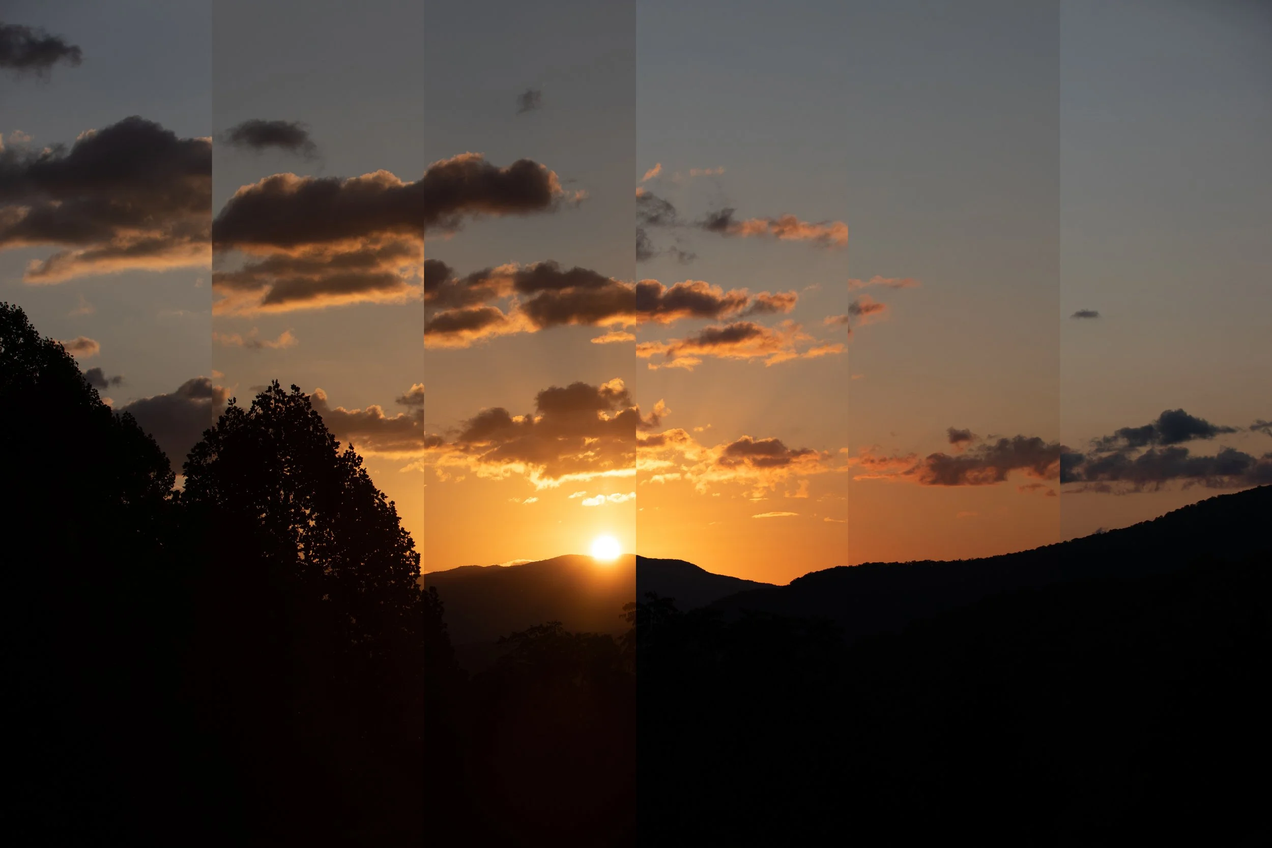 A sunset over a mountain landscape with scattered clouds in the sky.