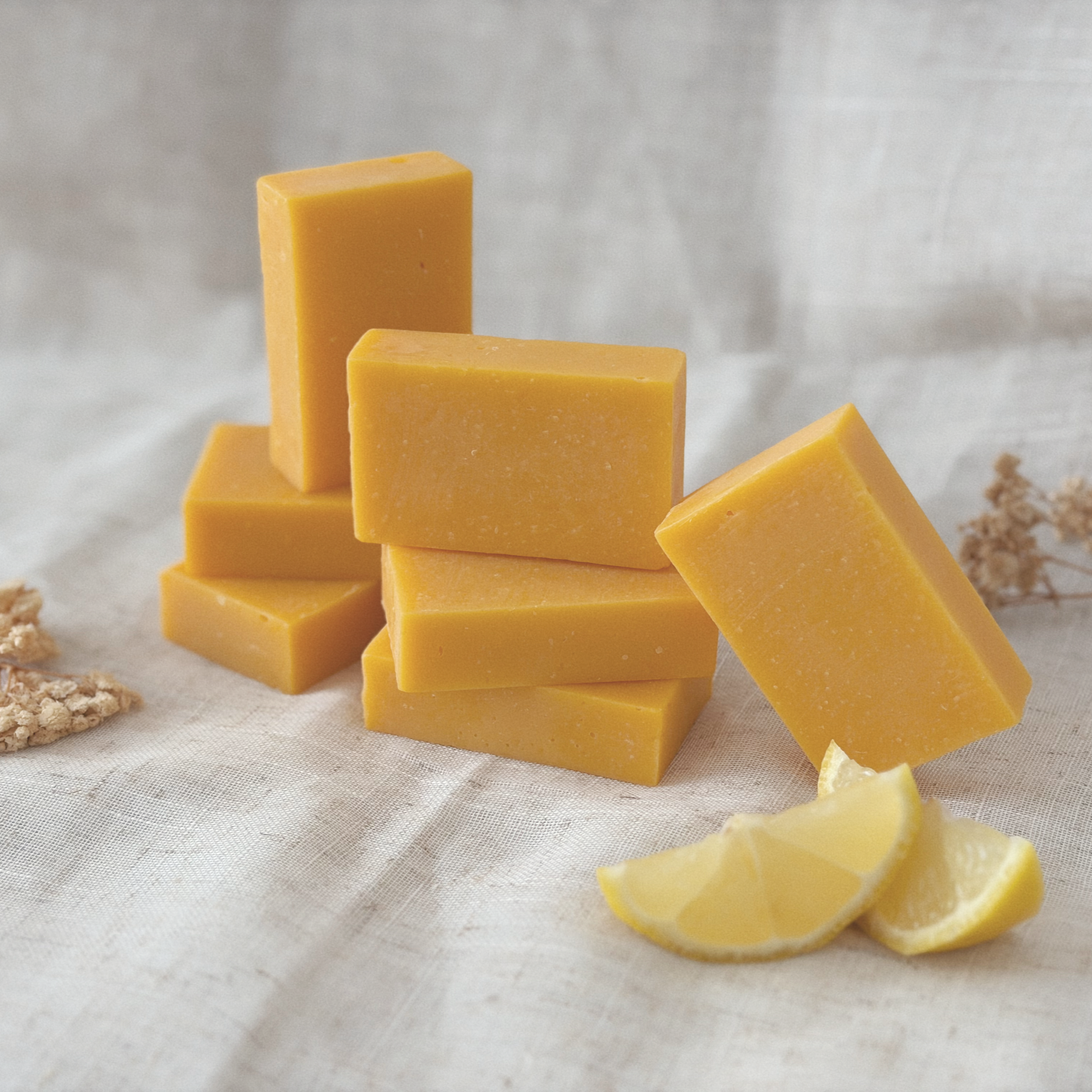 Several blocks of yellow cheese arranged on a light-colored cloth, with some sliced pieces and crumbs around.