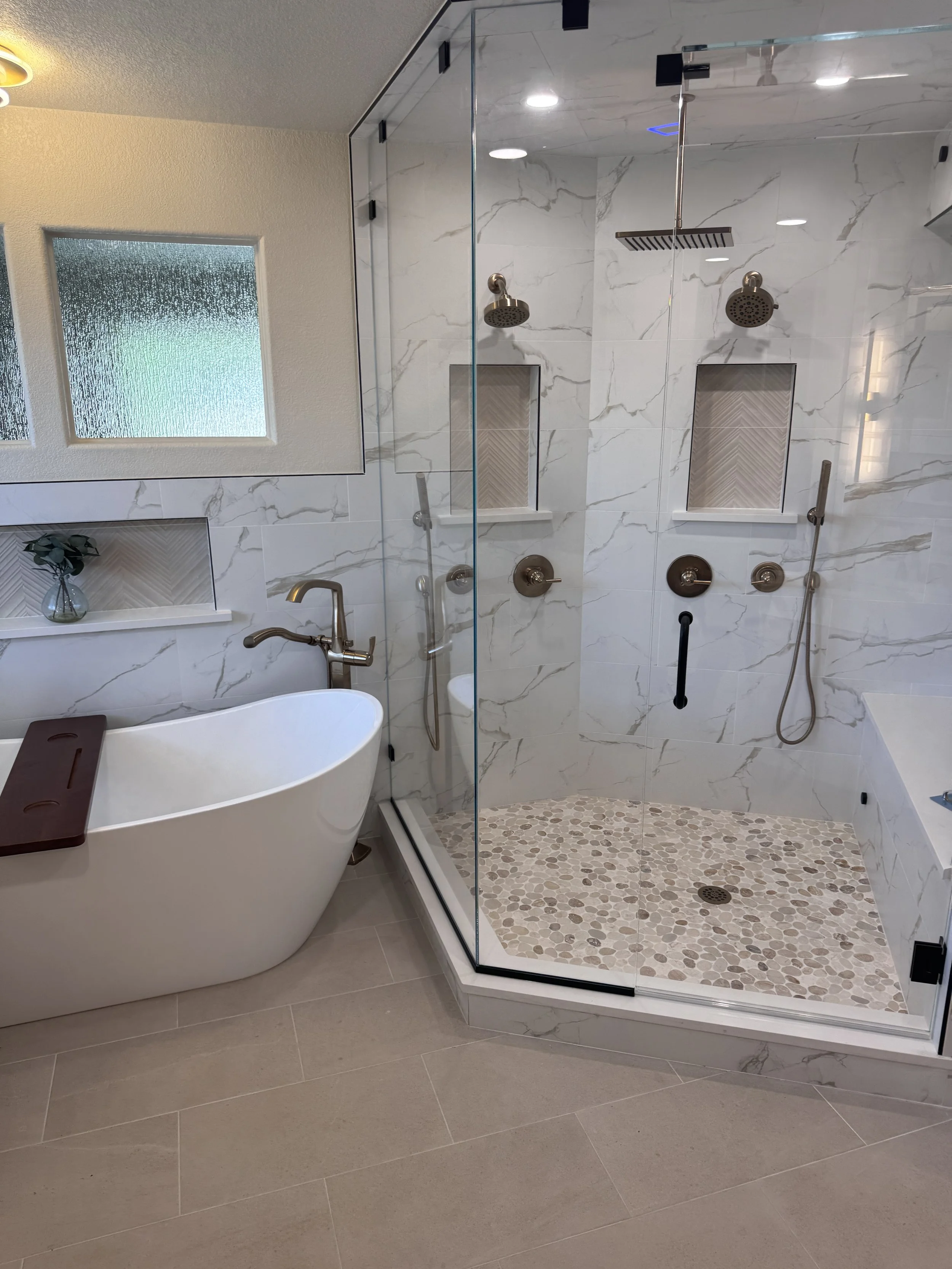 Modern bathroom with a walk-in shower, freestanding bathtub, beige floor tiles, and a frosted glass window.
