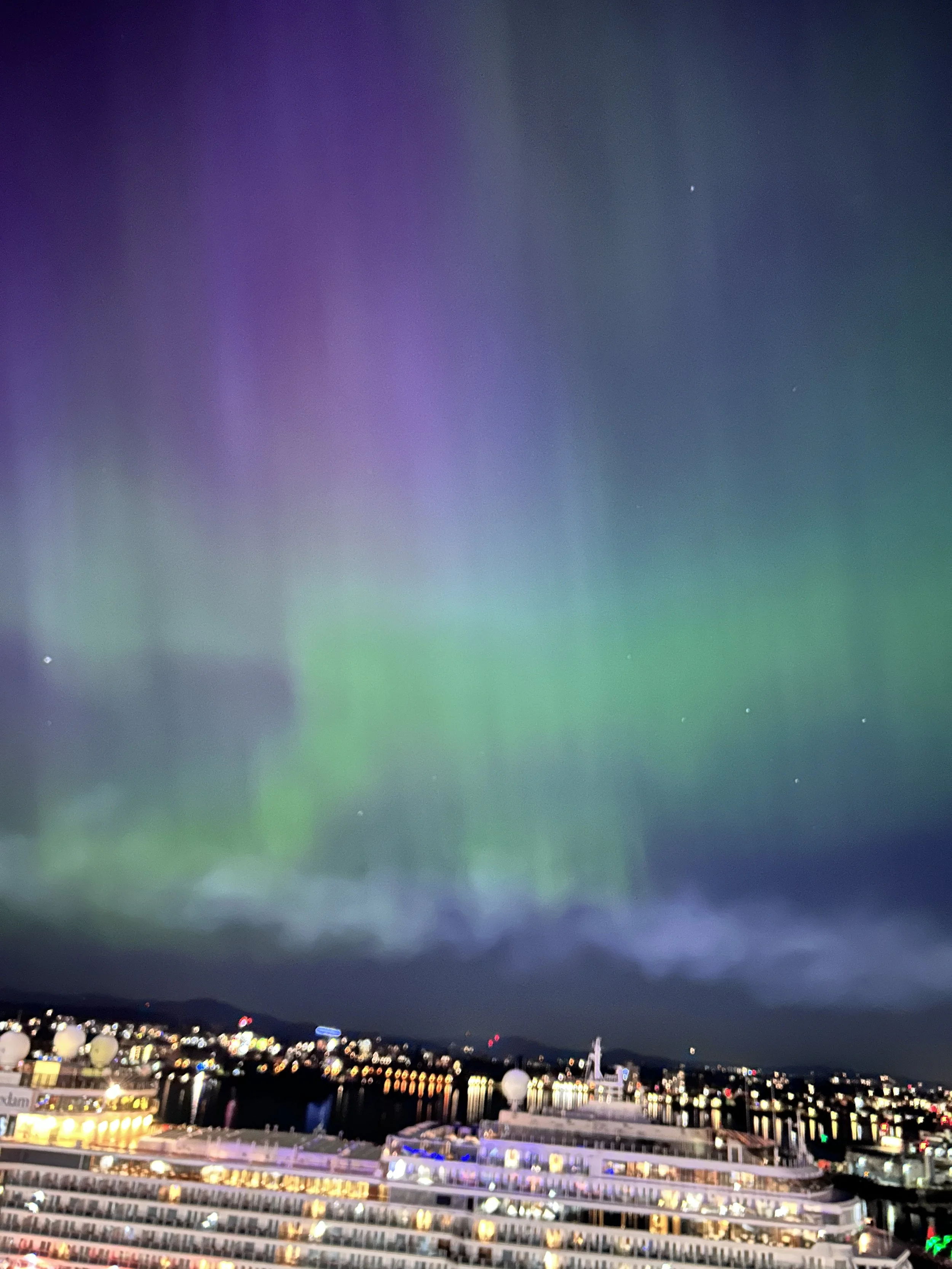 Nighttime cityscape with a cruise ship in the foreground and the Northern Lights in the sky, Northern lights from the cruise ship in Victoria B.C.