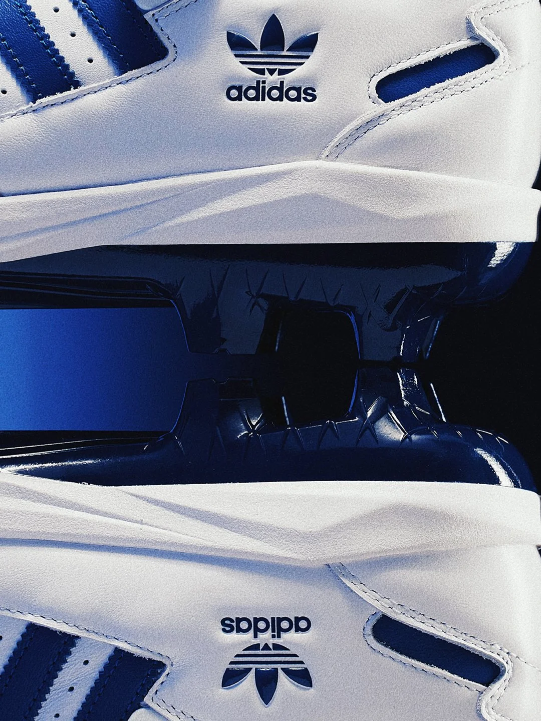 Close-up of a white Adidas sneaker with black and blue accents, showcasing the Adidas logo on the side and tongue of the shoe.