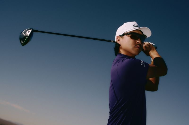 A man in golf attire holding a golf club ready to swing on a clear day.