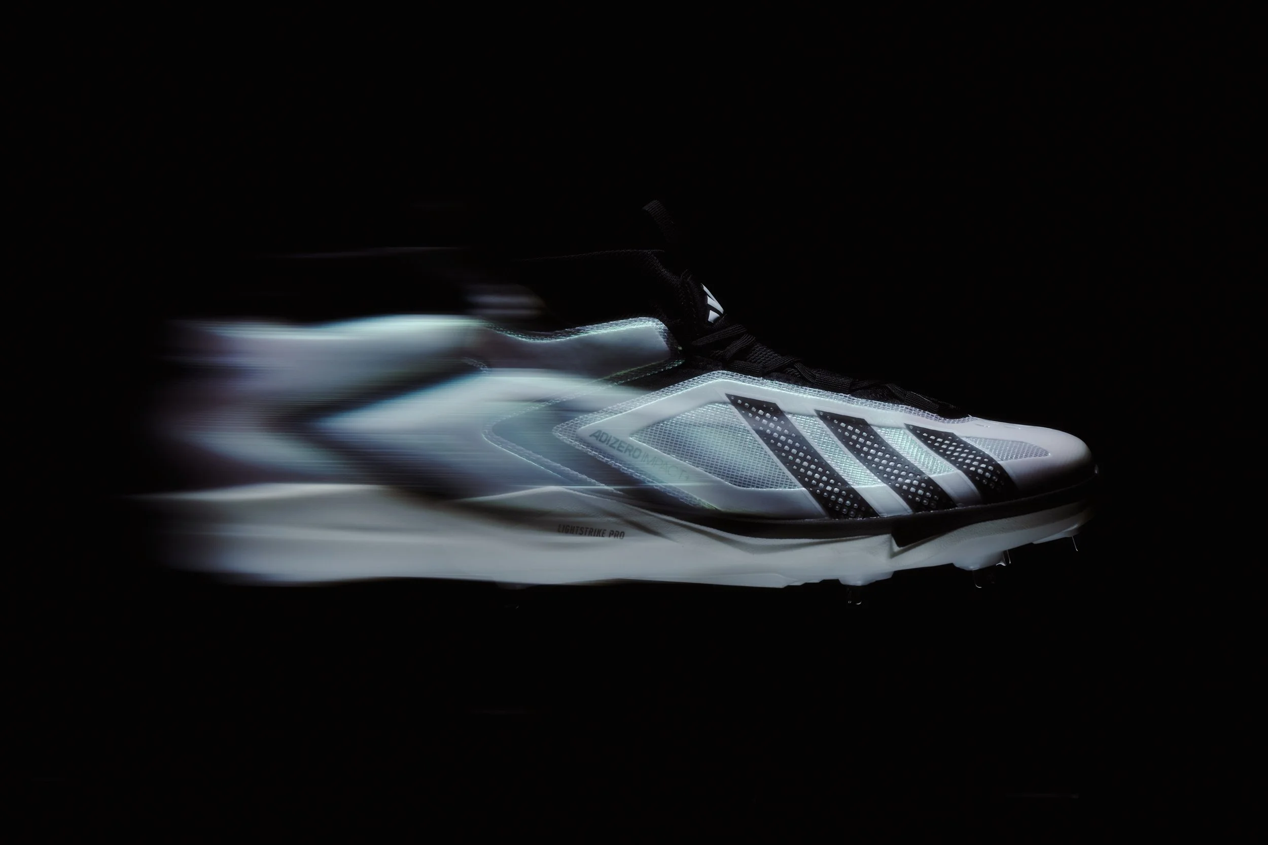 Lightly illuminated white athletic shoe with black accents, set against a dark background.