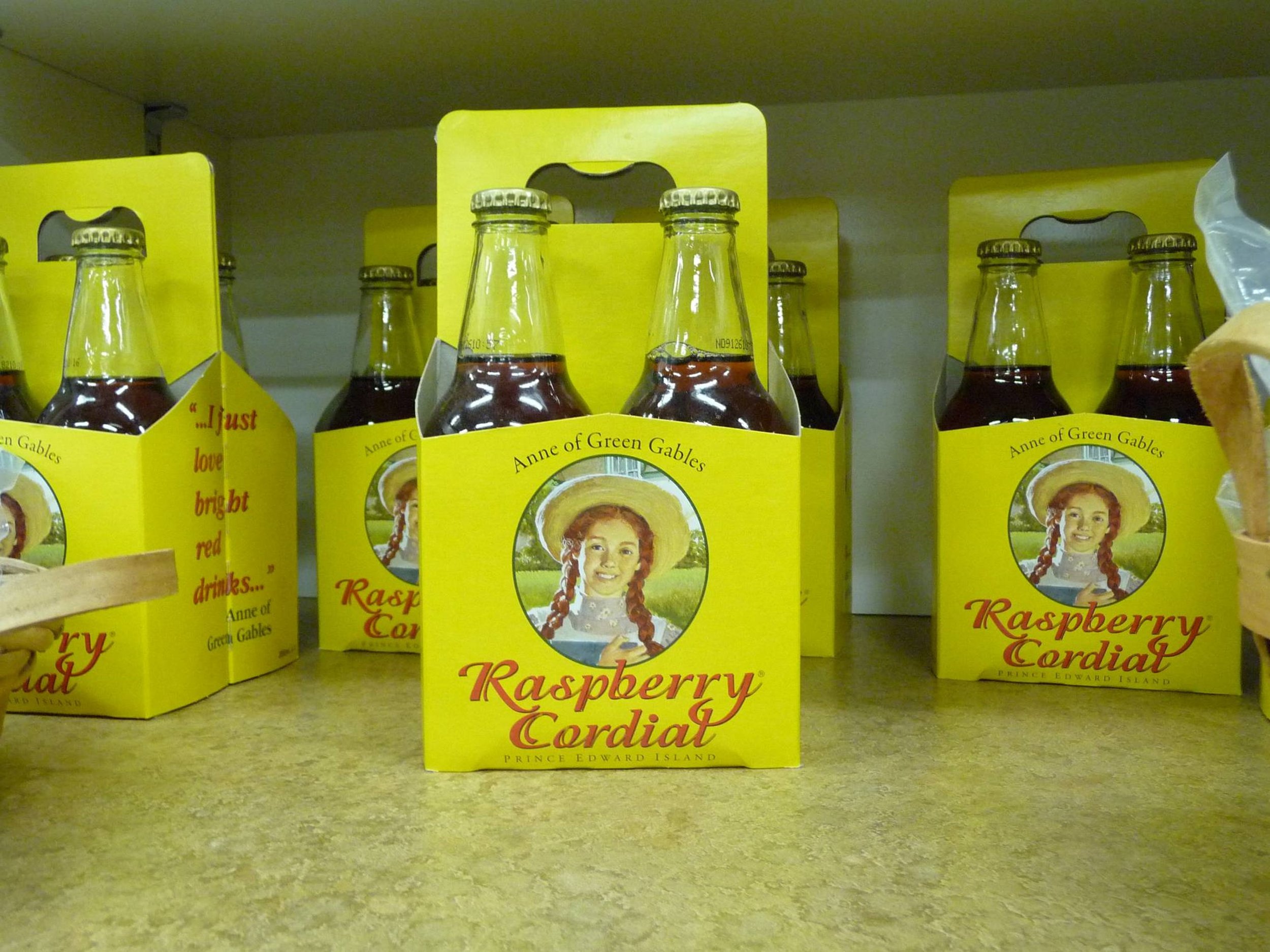 Boxes of raspberry cordial with yellow packaging and a writing image of a girl with red braided hair in a bonnet (Anne of Green Gables).