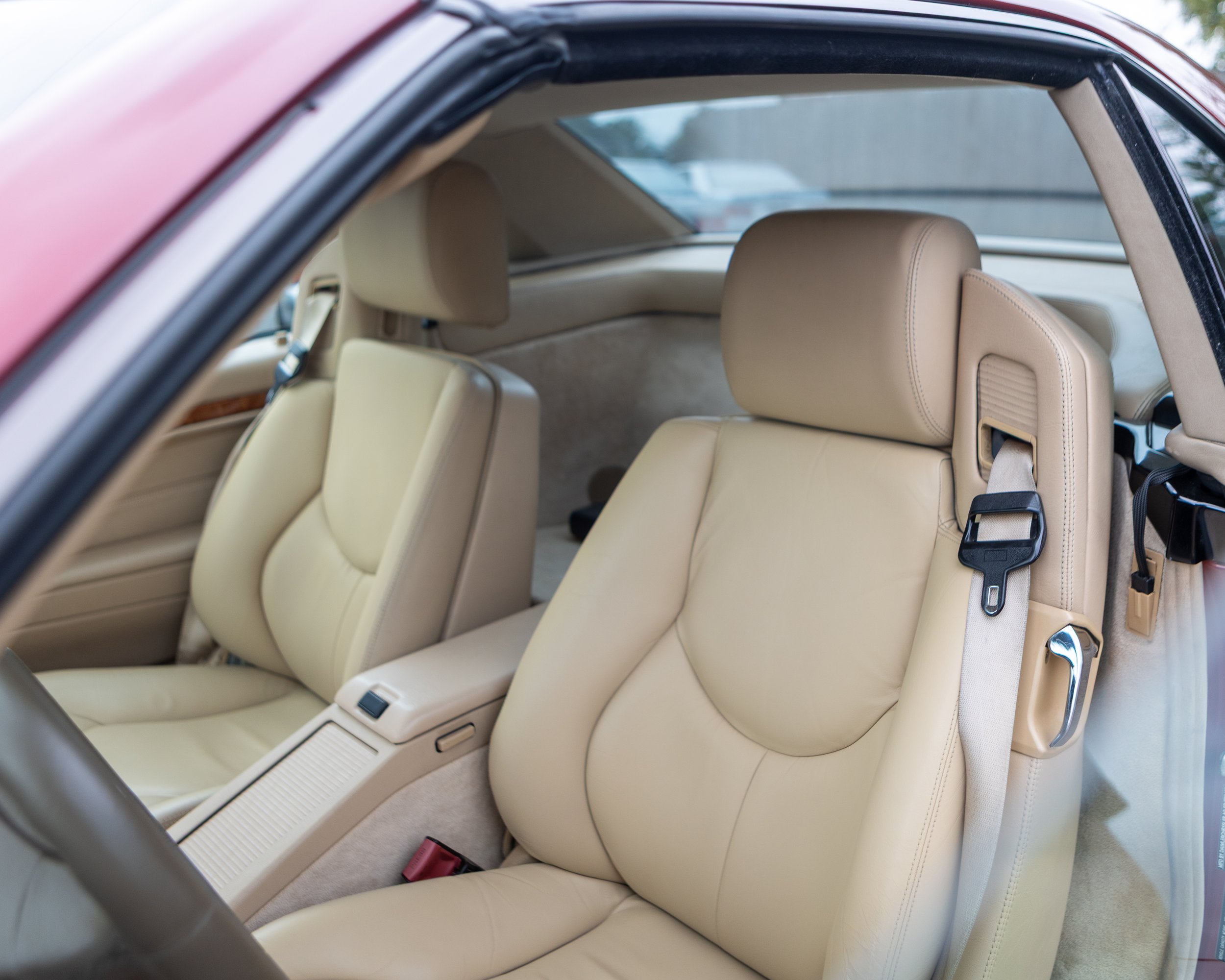 Interior of a luxury Mercedes-Benz vehicle showcasing the dashboard, steering wheel, and front seat, with a modern building visible through the windshield.