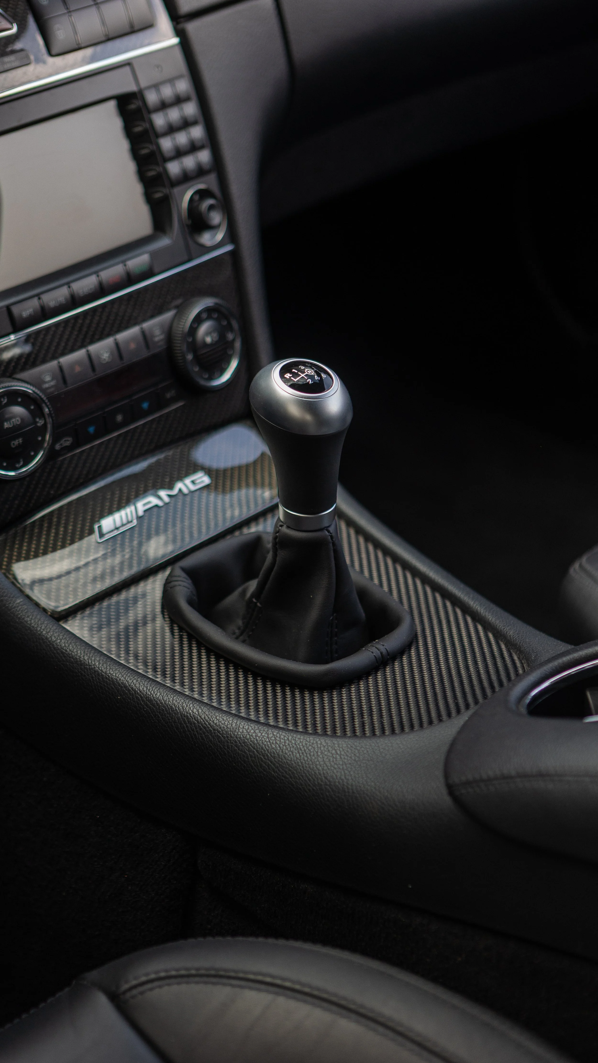Interior of a car featuring a manual gear shift, carbon fiber trim, and AMG branding.