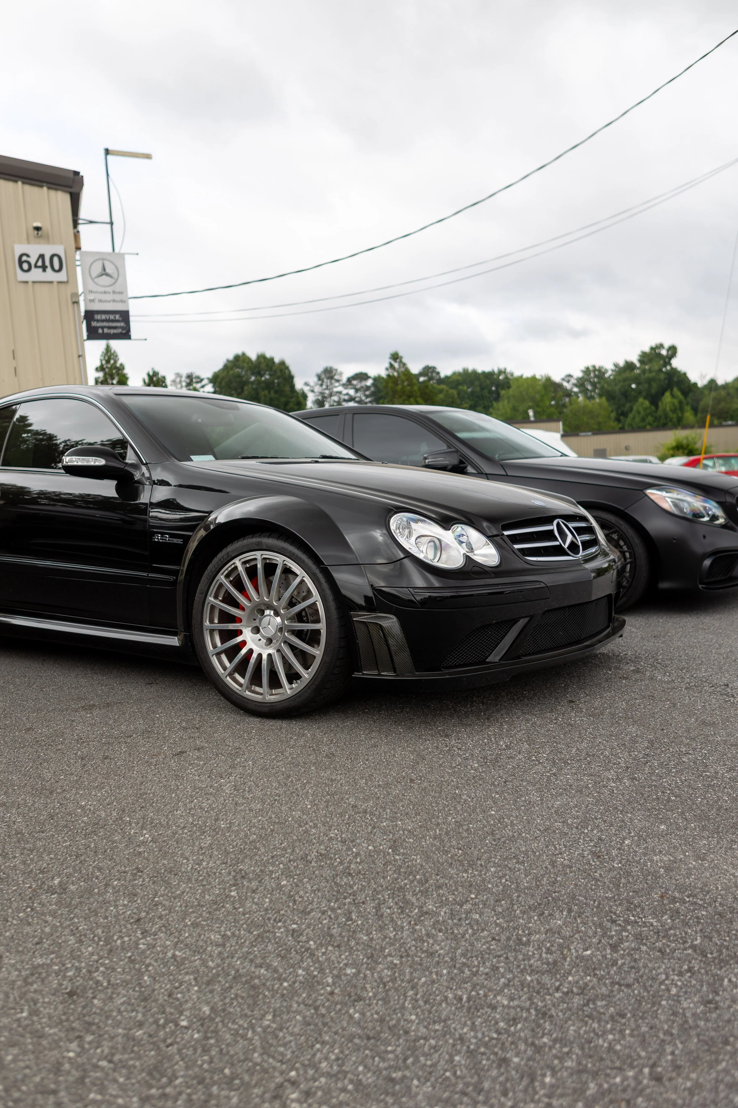 Black Mercedes-Benz and another black car parked in a parking lot outside a building with a Mercedes-Benz sign and address 640.