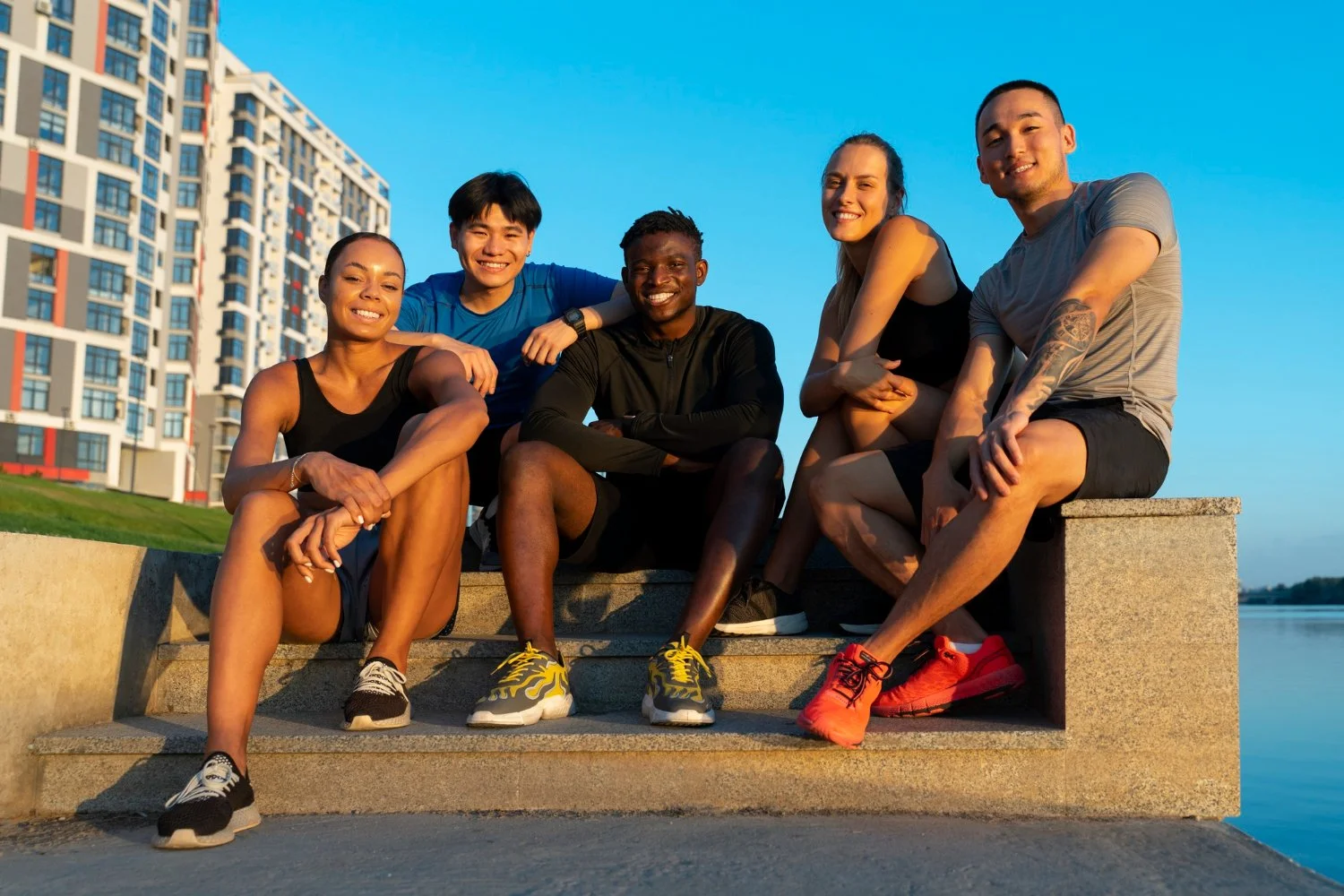 Run Collective team members relaxing together after a corporate run club session, with the city skyline at sunset.