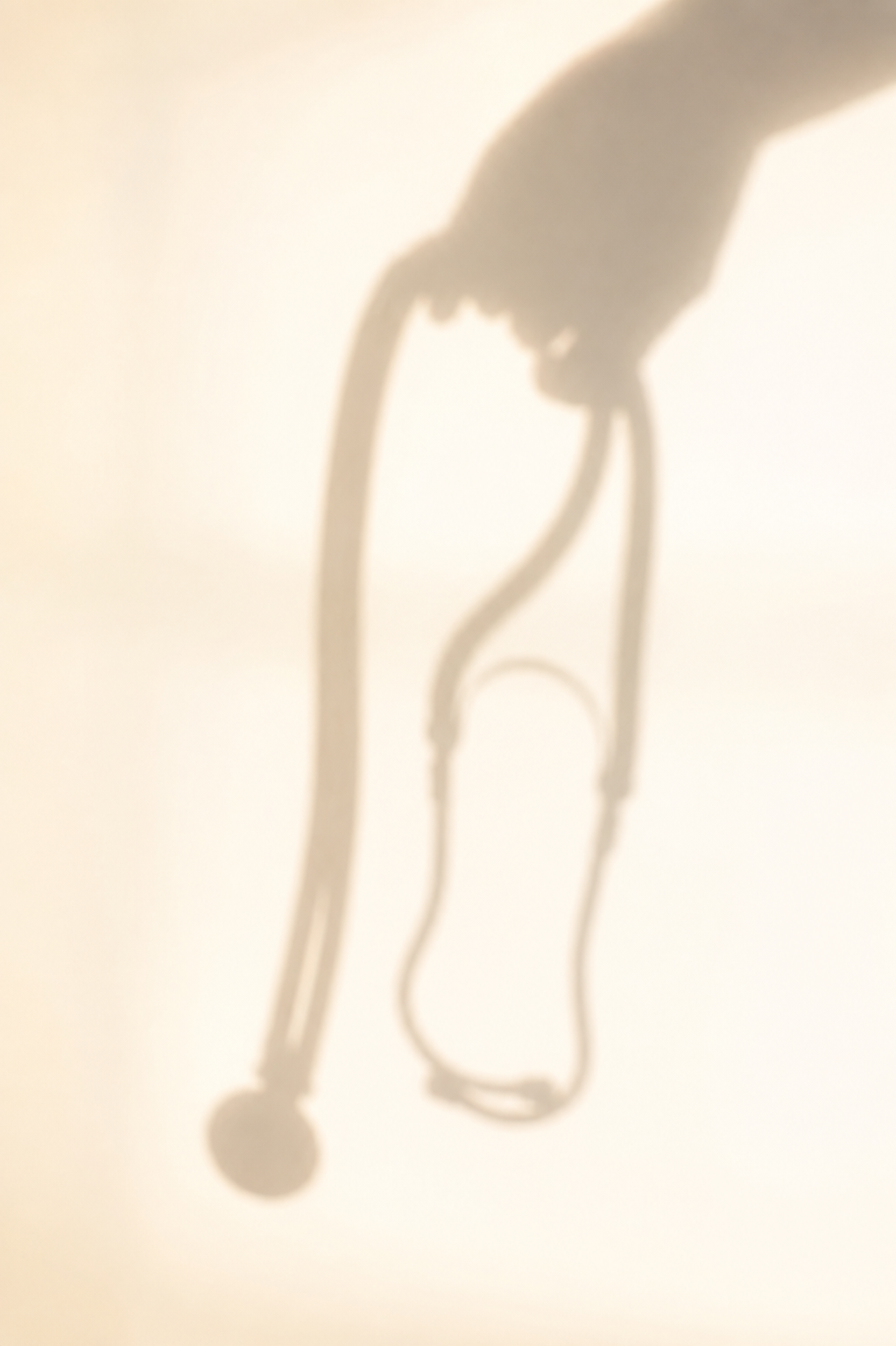 Shadow of a person using crutches on a plain wall.