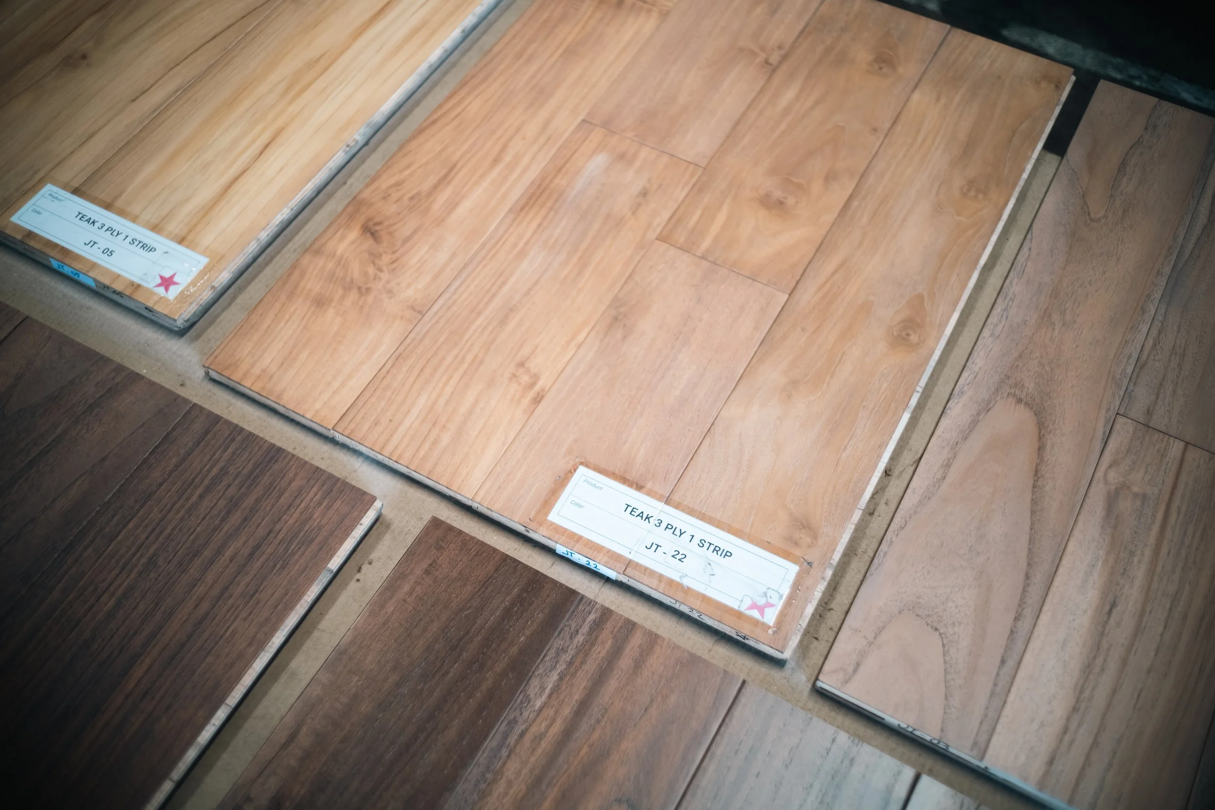 Samples of wood flooring planks in different shades and grain patterns displayed on a table at a flooring store.