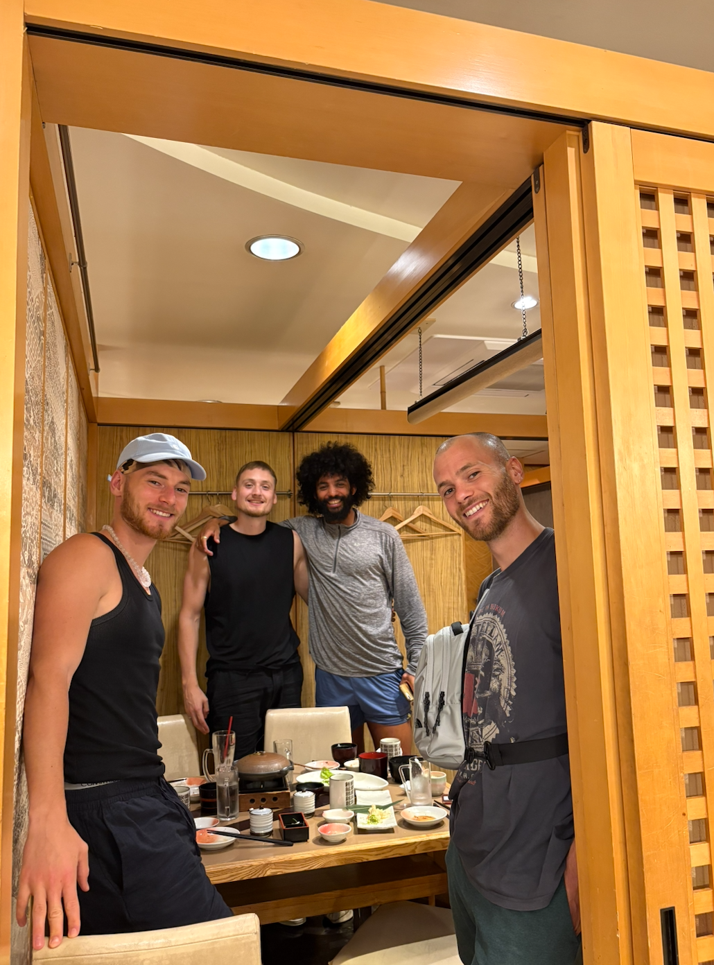 Four men smiling at a dinner table in a Japanese restaurant.