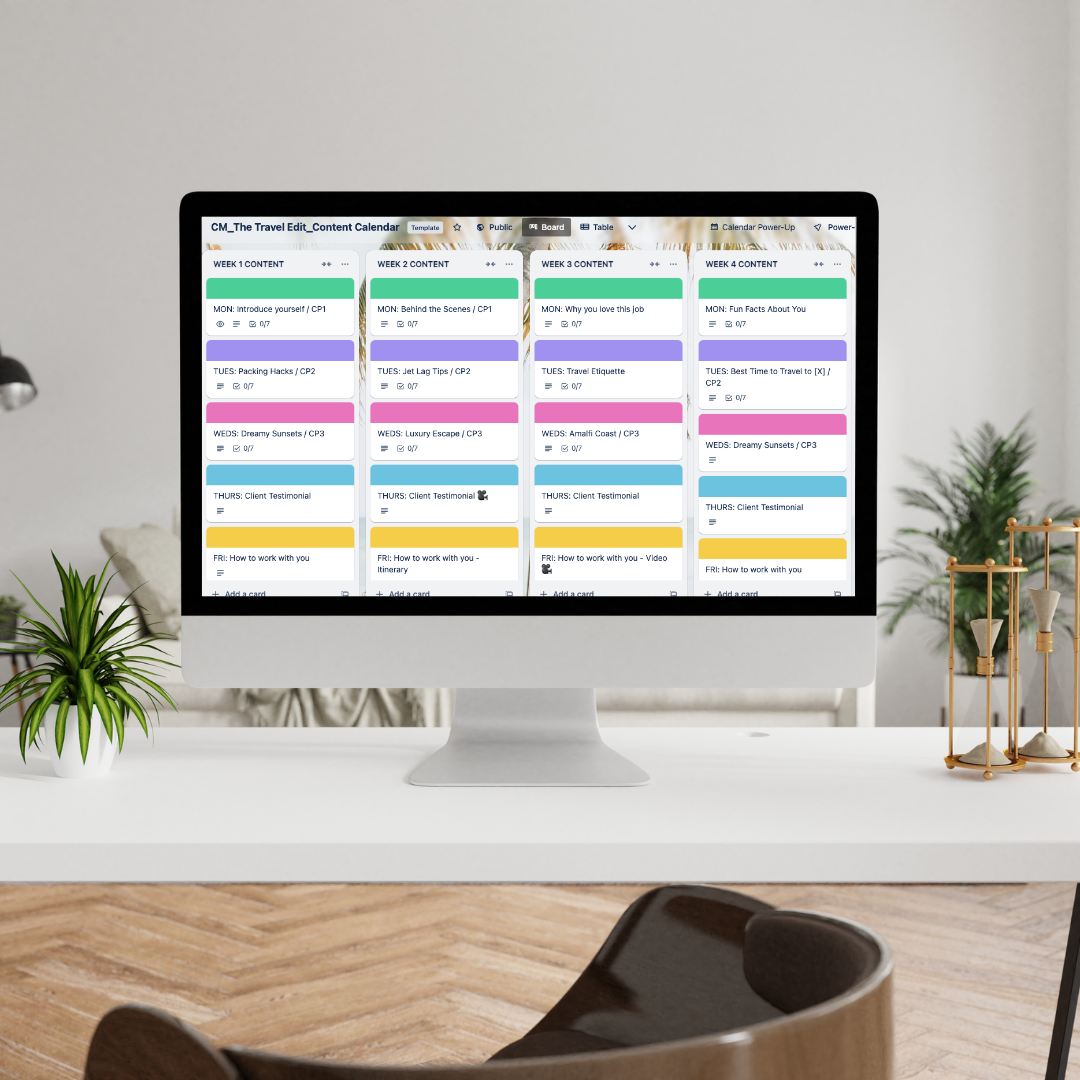 Computer monitor displaying a content calendar with colorful rows for different weeks and topics, sitting on a white desk with a small plant to the left and decorative items to the right, in a modern office setting.