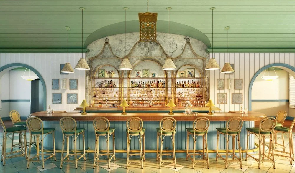 Interior of a vintage-style bar with a curved wooden counter, gold accents, and twelve barstools. Shelves behind the bar display bottles and framed pictures. Pendant lights hang above the counter, and nautical decor is present.