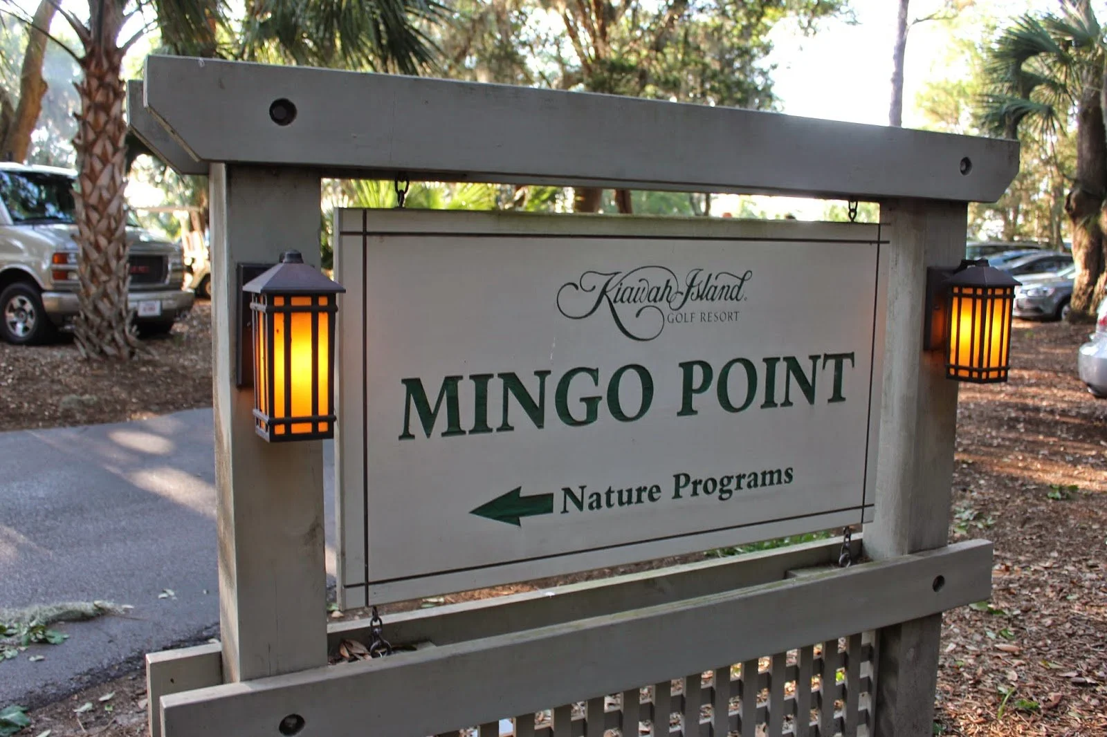 Sign for Mingo Point at Kiawah Island Golf Resort, directing to nature programs with an arrow pointing left, flanked by two lit lanterns.
