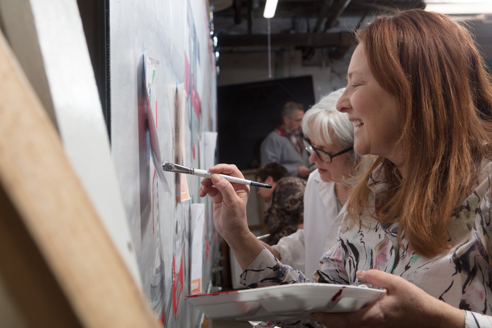 Women working together on a creative project at a whiteboard, drawing and writing.