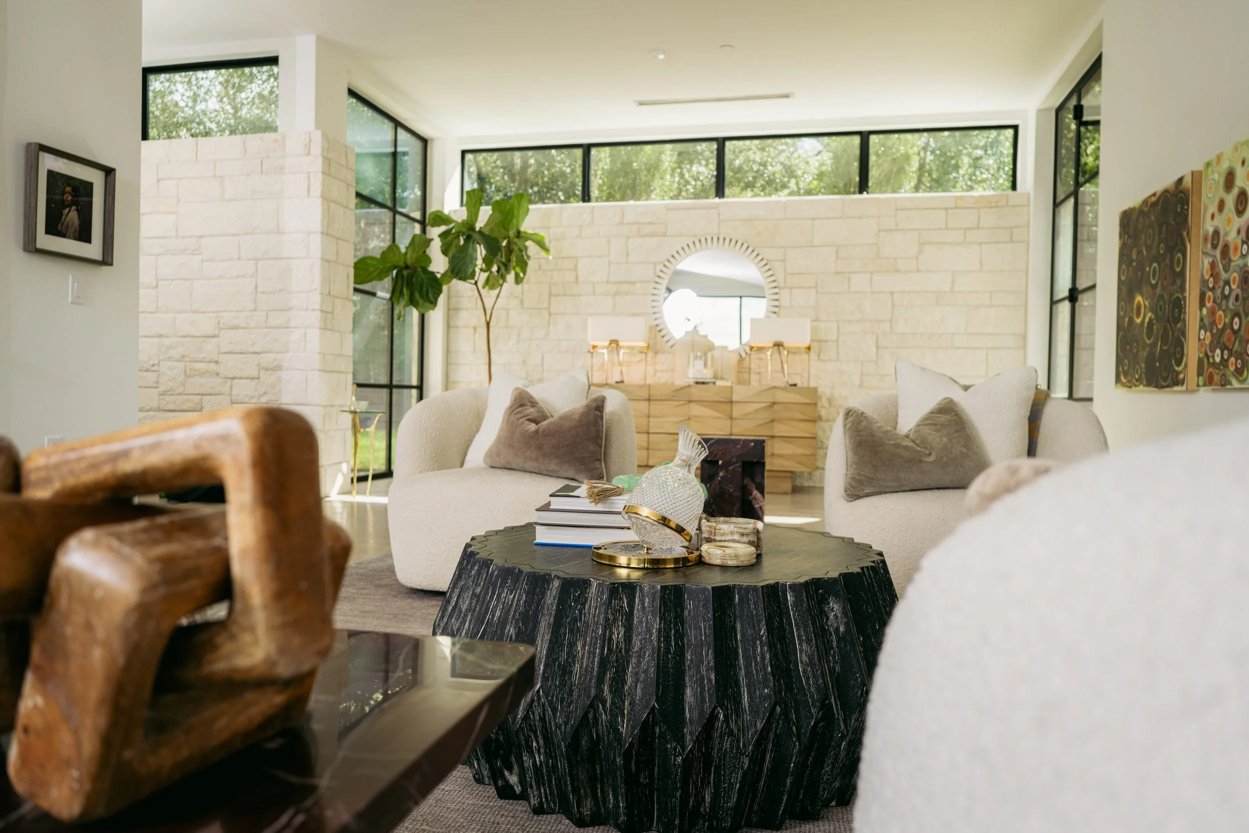 A carved wood sculpture in the foreground, the living room and limestone wall beyond.