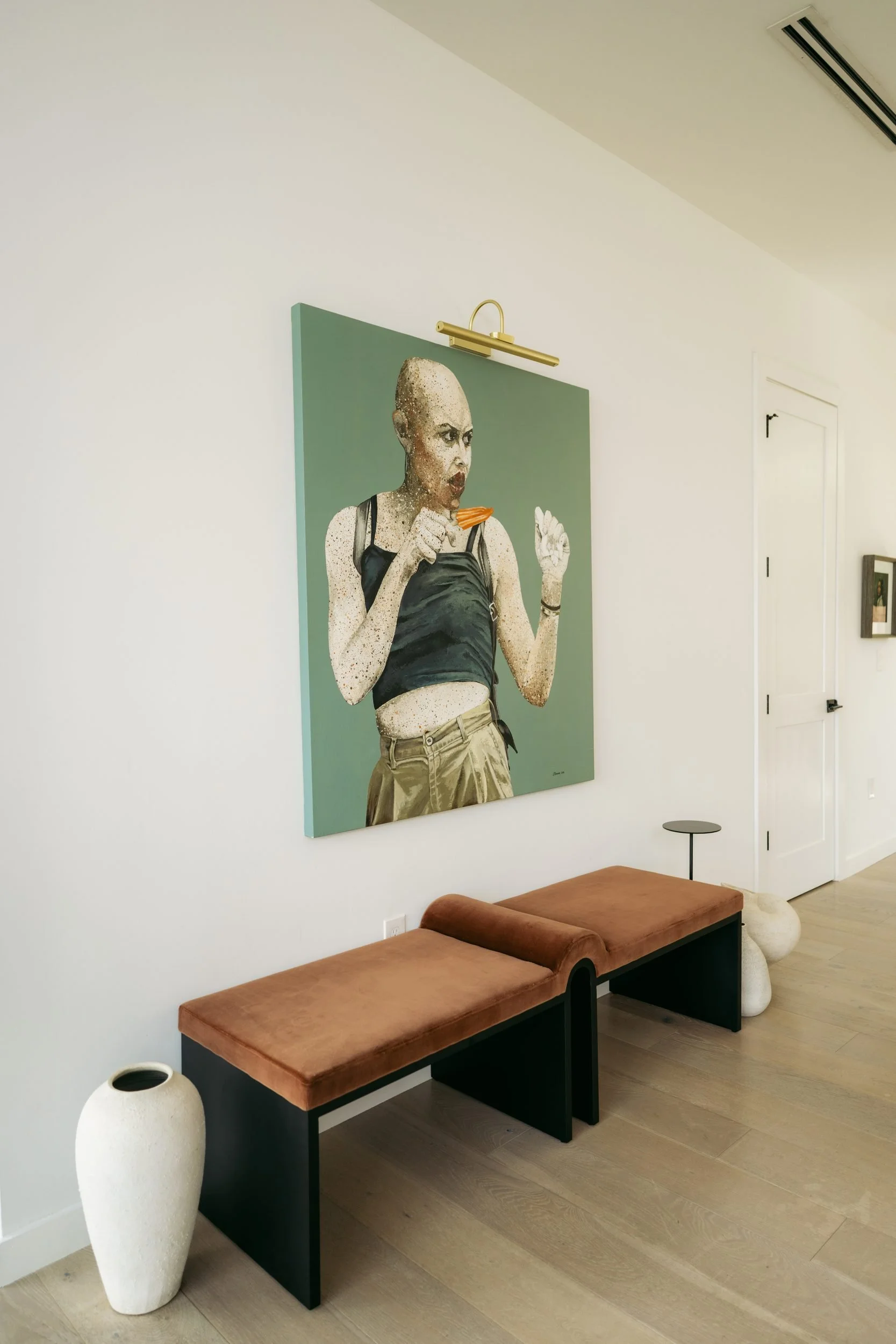 A large-scale portrait above a cognac leather bench.