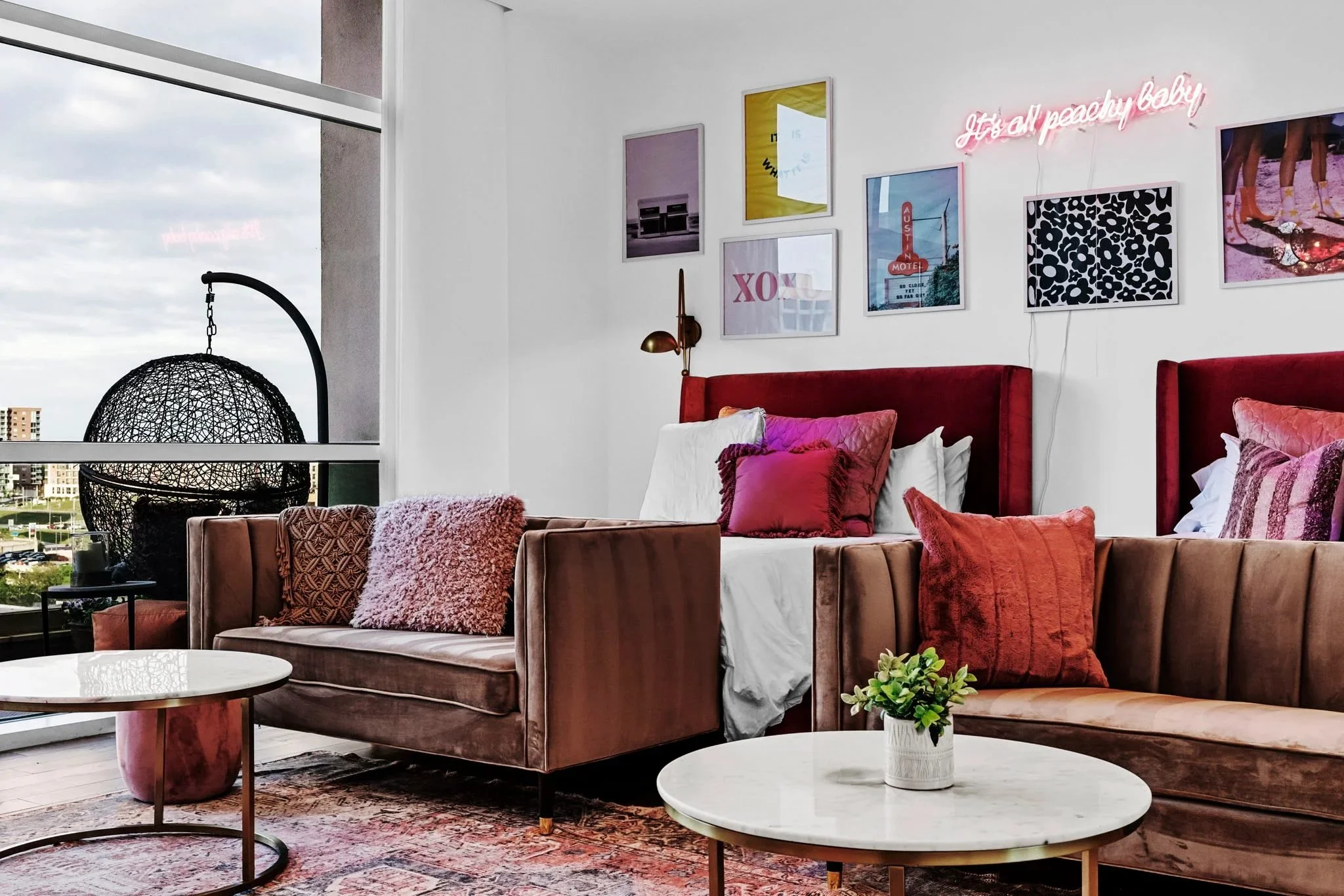 A bedroom in rose and rust velvet, with a gallery wall and a hanging chair.