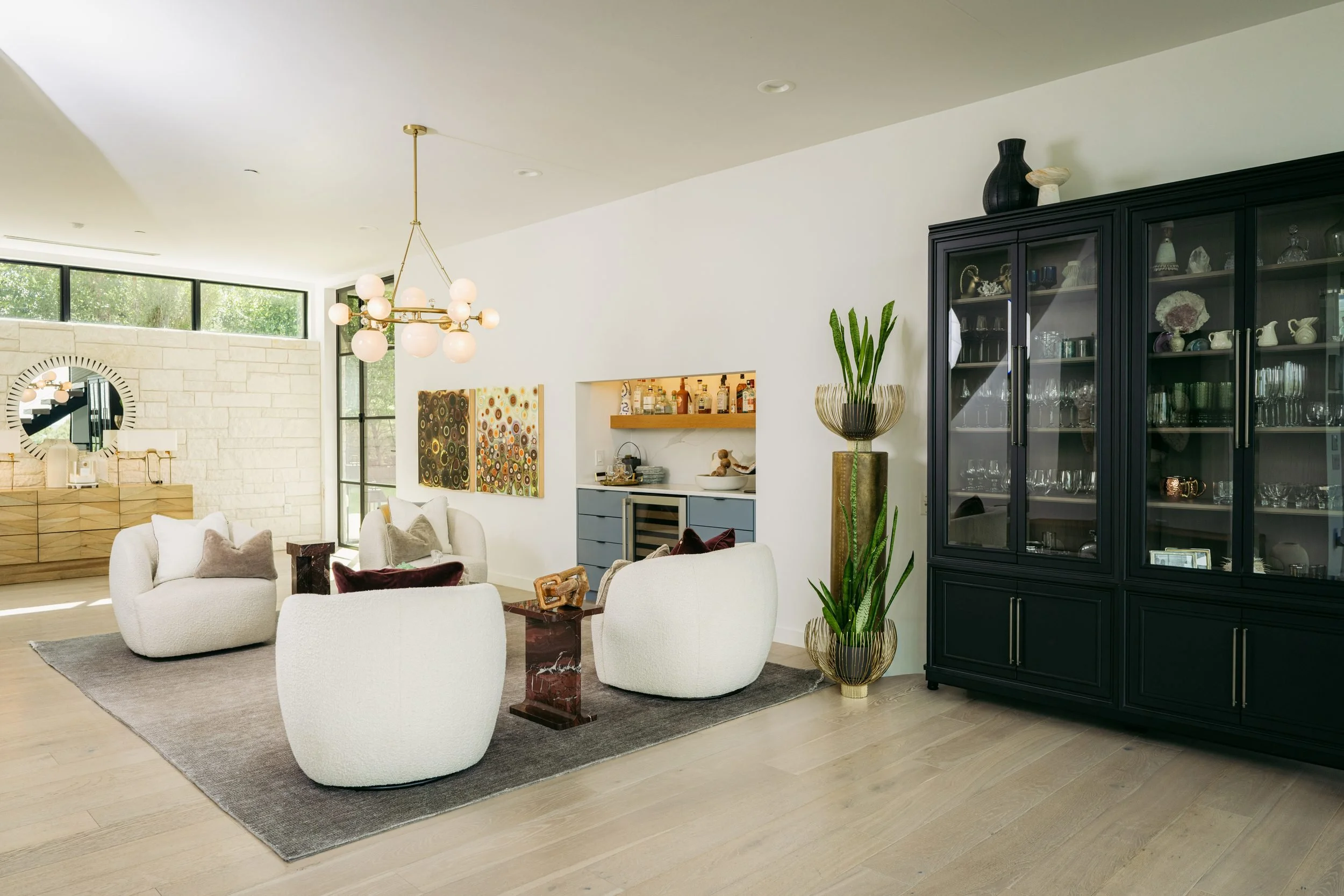 The great room opening to a black glass-front cabinet, the bar niche and a wall of clerestory windows.