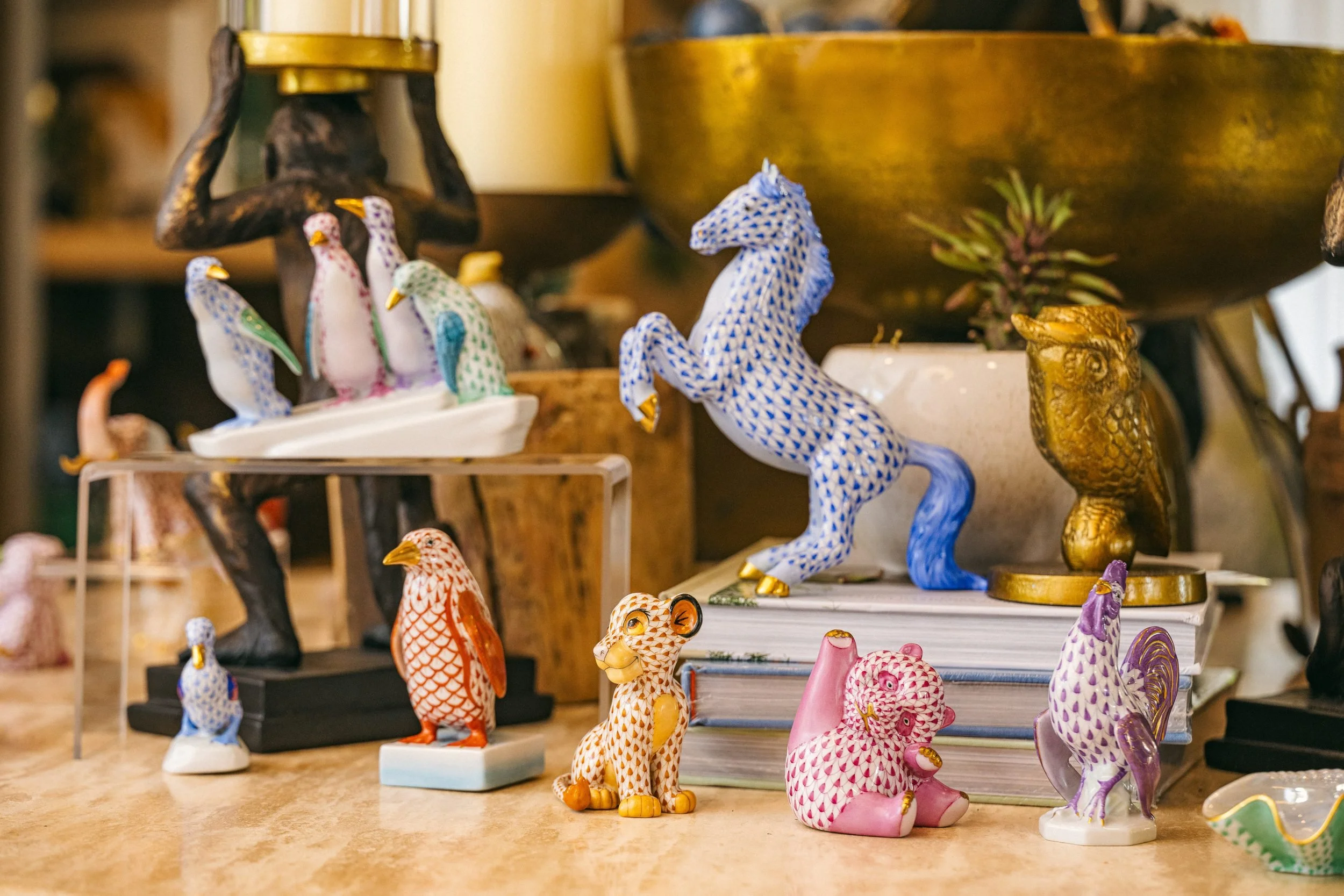 Hand-painted porcelain animals gathered on a travertine table.
