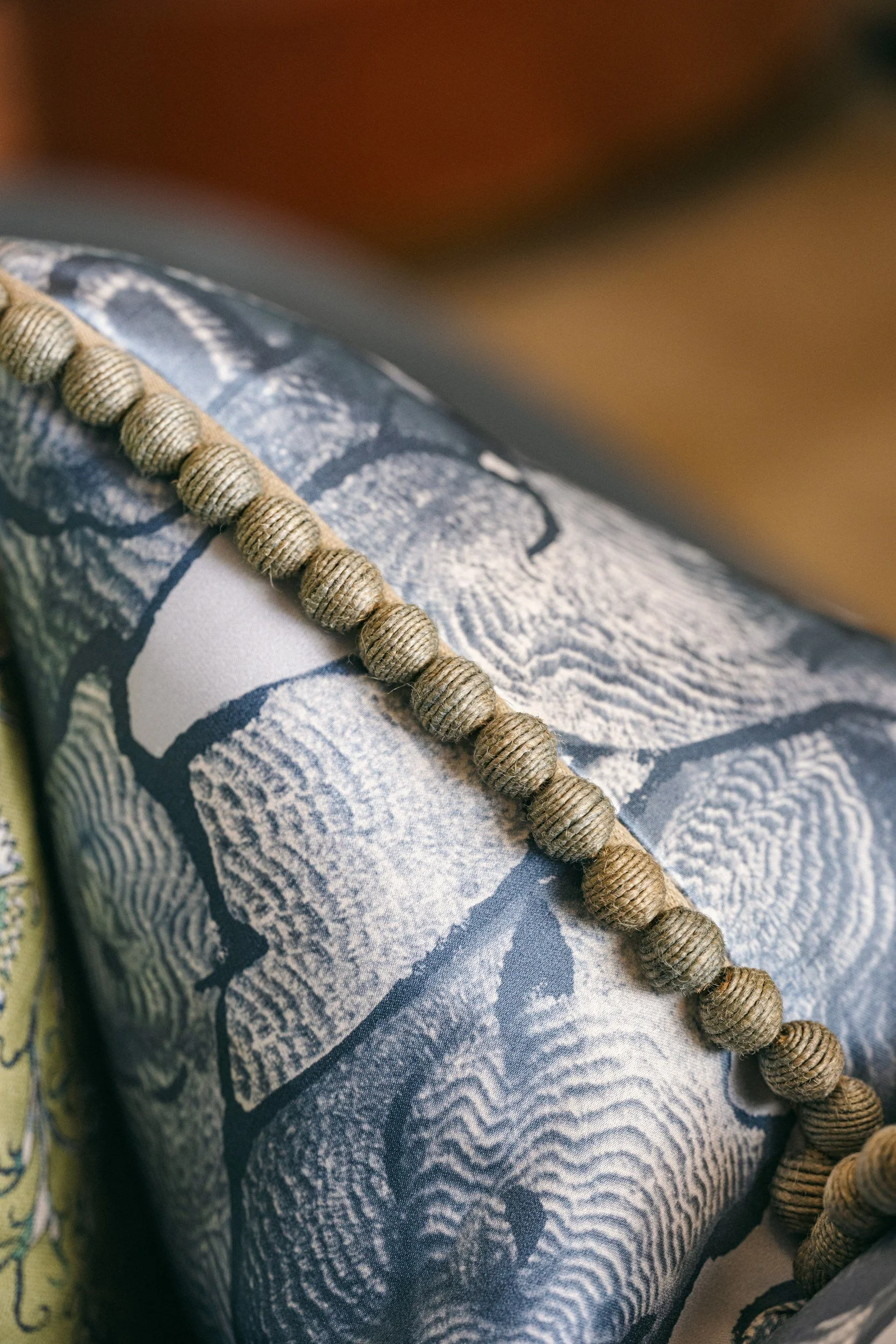 A string of round, beige beads on a textured fabric with black and white patterns.