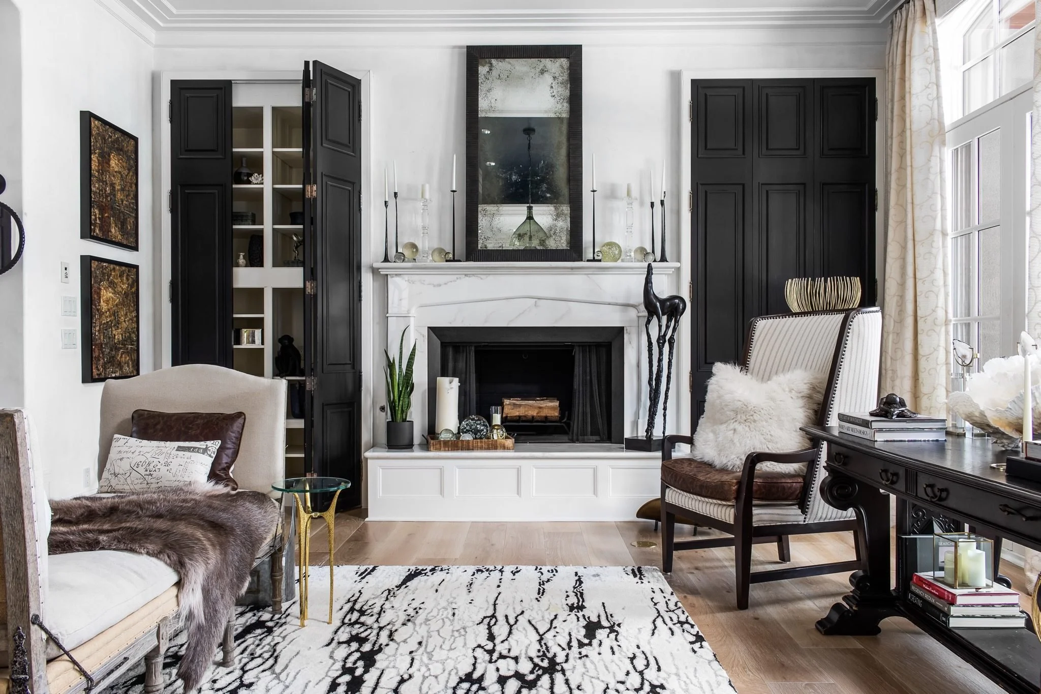A living room of black-lacquered doors, a white fireplace and a graphic rug.