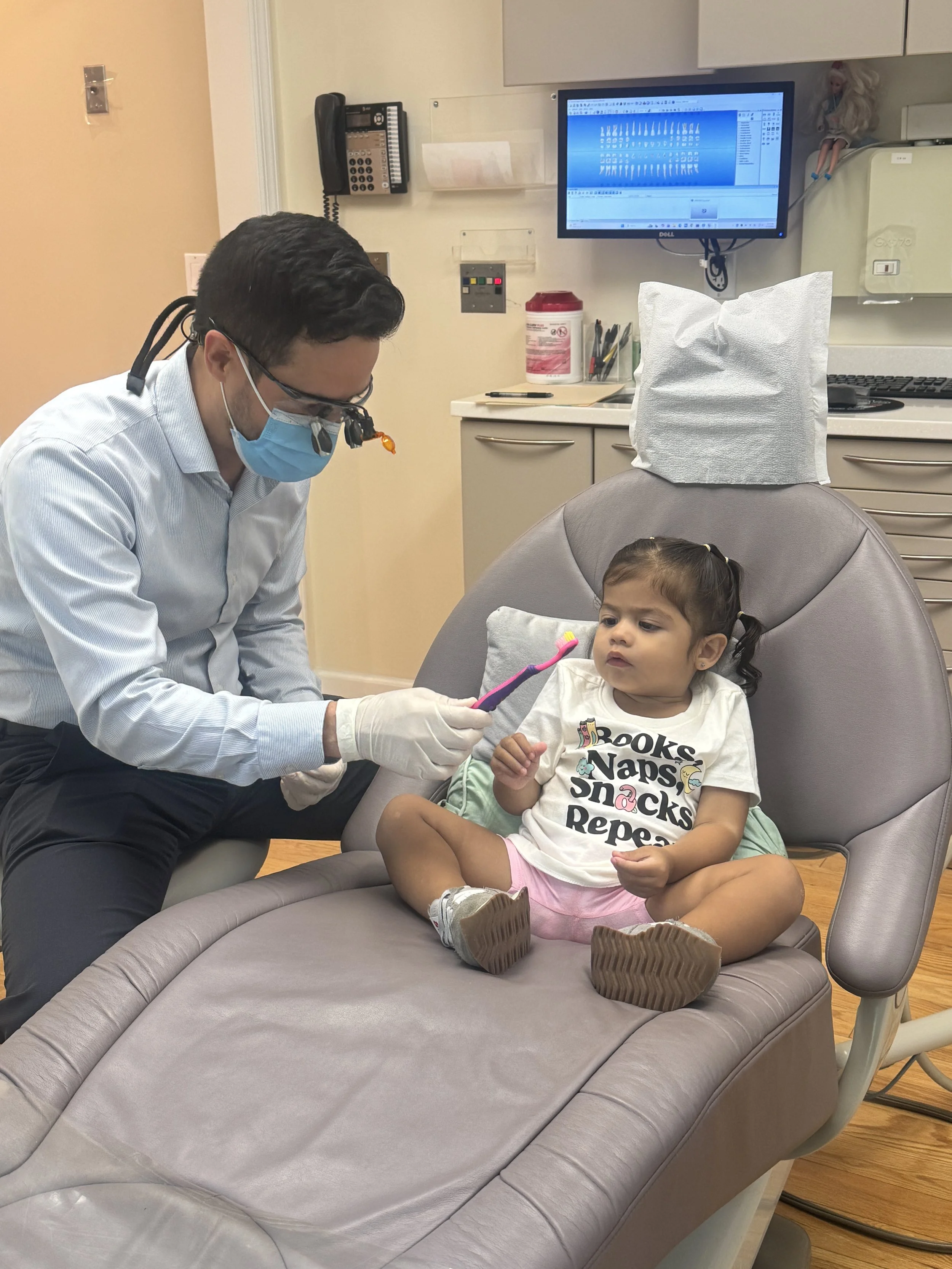 Dr. DiMaggio giving toothbrush to child
