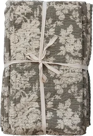 Stack of folded fabric with floral lace pattern, tied with a white ribbon.