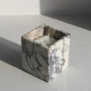 Marble cube with white decorative stones inside, placed on a white surface.