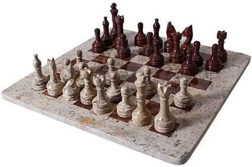 Chessboard with carved chess pieces on a marble surface.