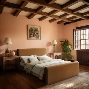 A bedroom with peach-colored walls, a beige bed with white bedding, two bedside tables with lamps, a framed picture, a large window, a plant, and wooden ceiling beams.