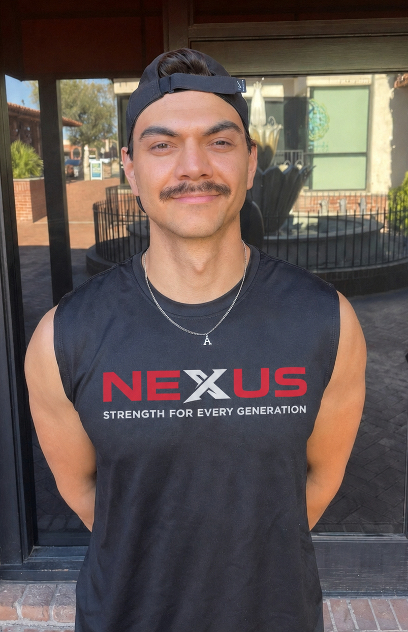 Young man with mustache wearing a black sleeveless shirt with 'NEXUS' logo and slogan, standing outside in front of glass door