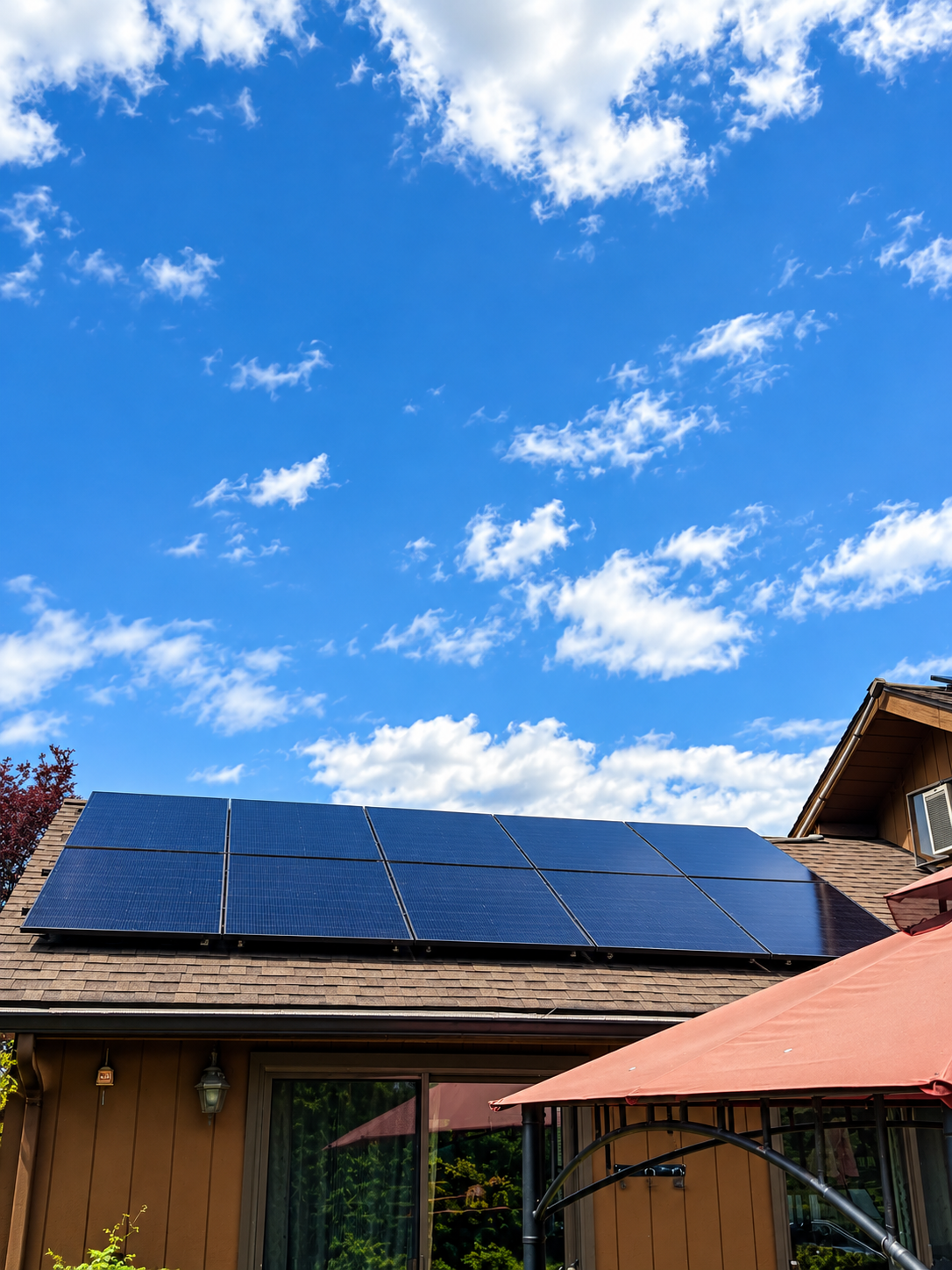 Completed rooftop solar array on a brown-sided home, photographed from the backyard