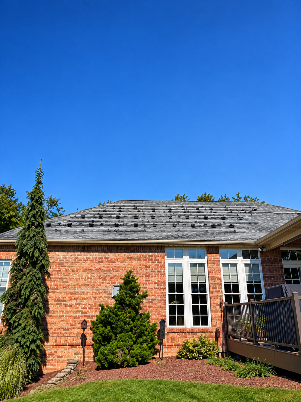 Brick home with solar panels removed and roof mounting attachments visible