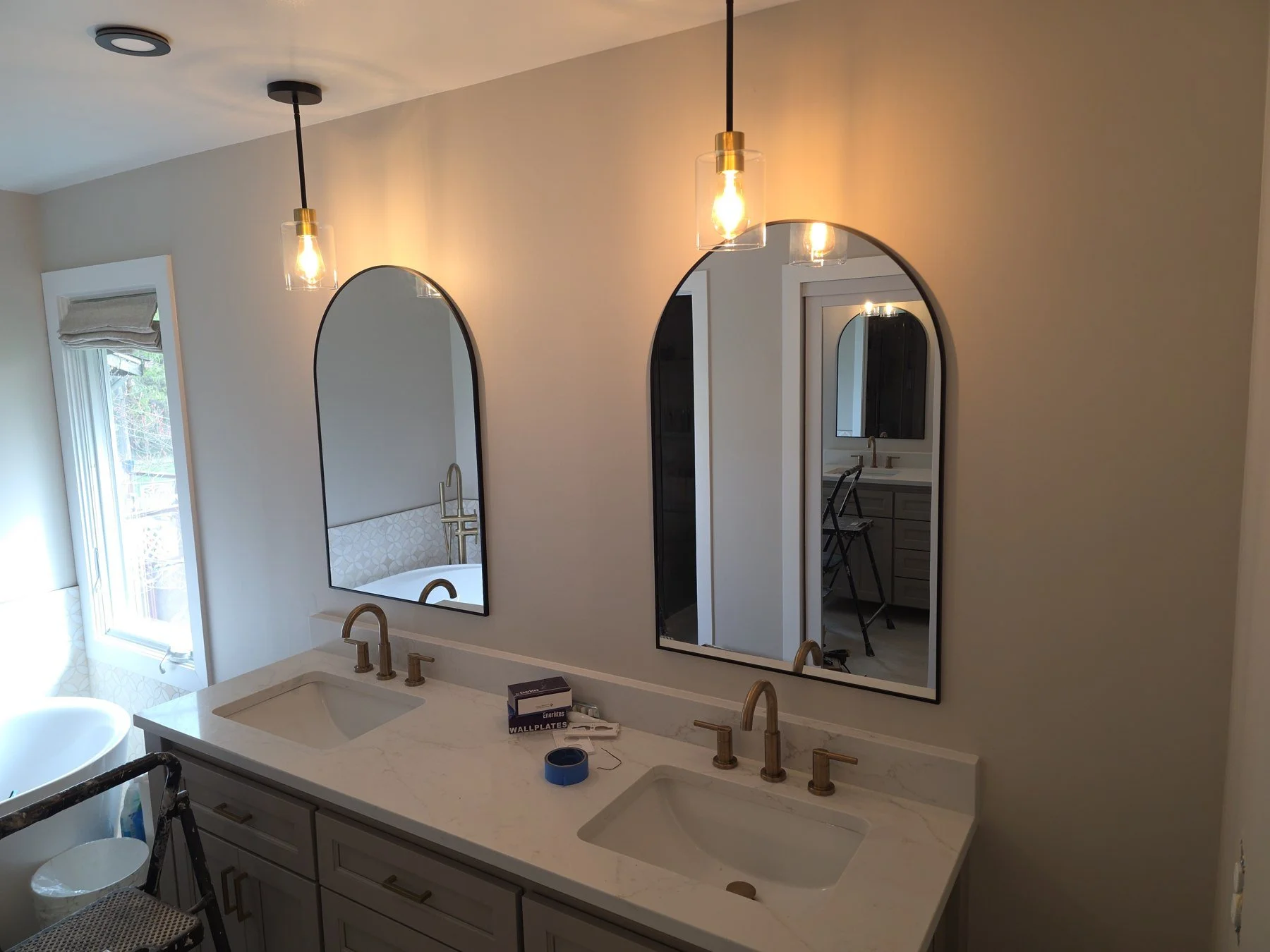 Double vanity with twin arched mirrors and pendant lighting during bathroom finishing